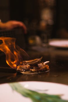 Exciting image of a chef grilling meat with an open flame in a restaurant setting.