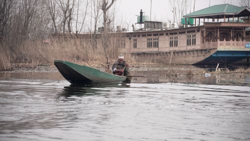 Free Peaceful scene of man in a rowboat on a calm lake with rustic houseboat. Stock Photo