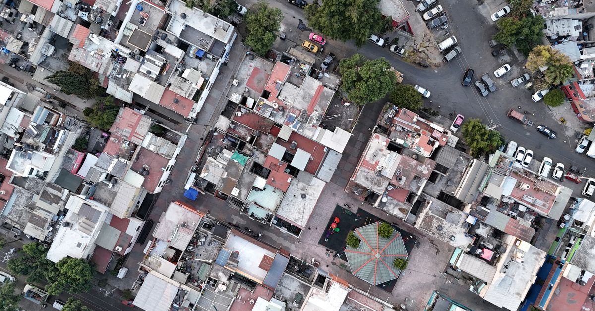 High-angle shot of densely packed urban residential area with streets and vehicles.