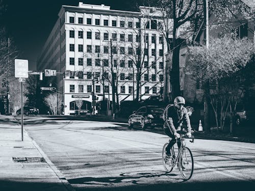 Grayscale Photo of Man Riding Bicycle on Road