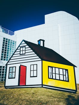 阳光明媚的日子里，卡通风格的房屋雕塑与现代建筑立面相互映衬