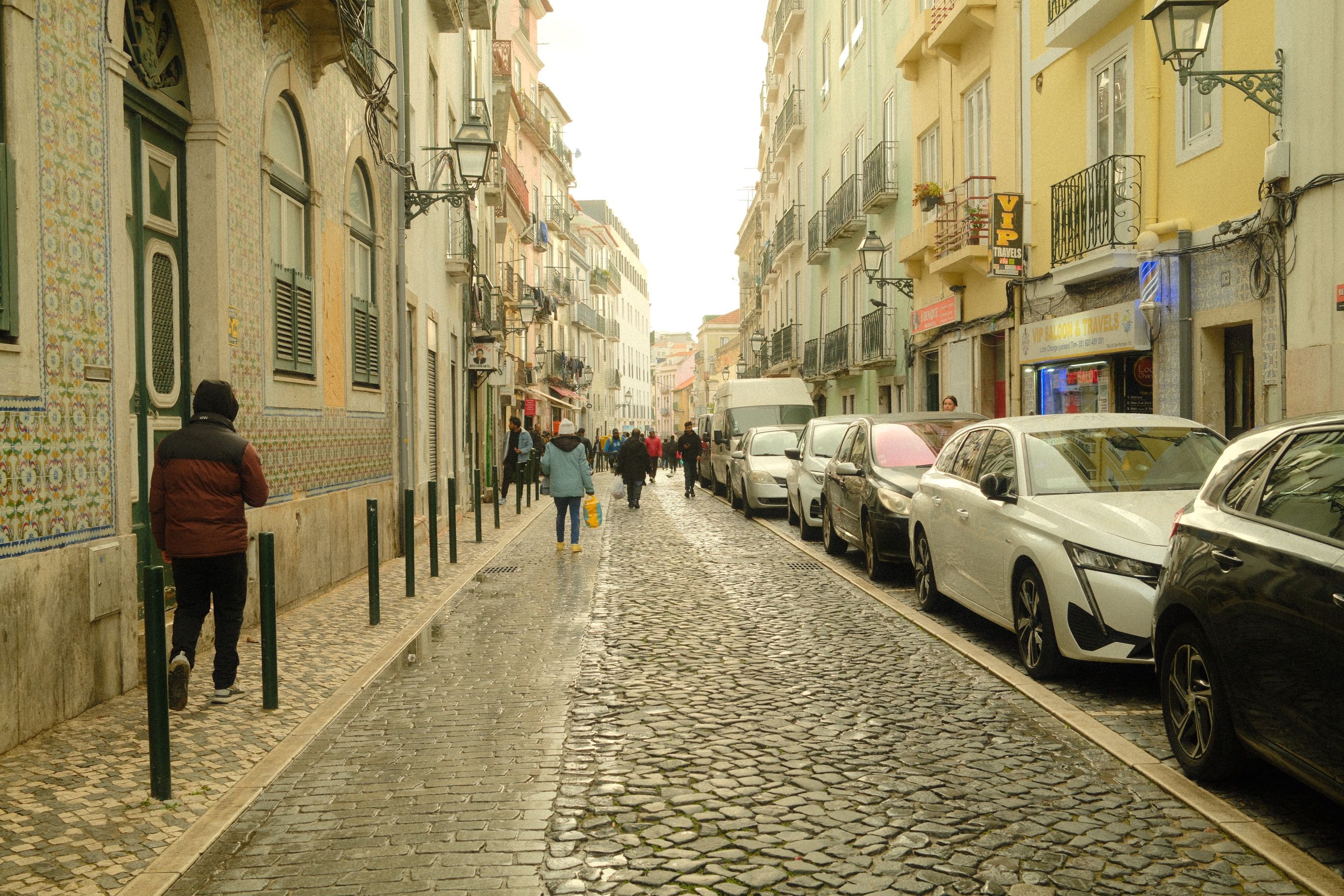 Polished limestone calçada pavement on a steep Lisbon street with a handrail