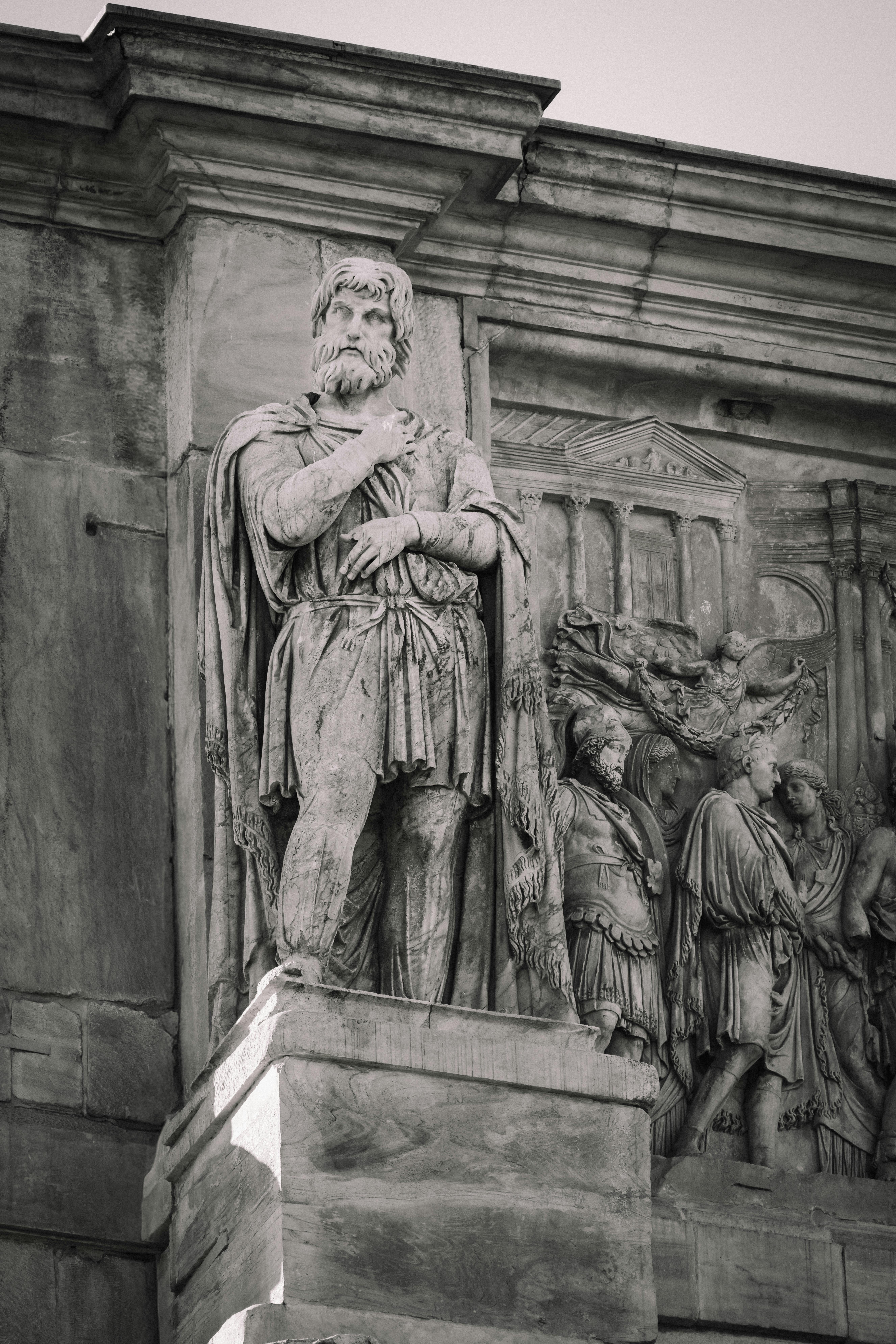 Gratis Foto in bianco e nero di una grande statua in pietra sulla facciata di un edificio storico con sculture classiche. Foto a disposizione