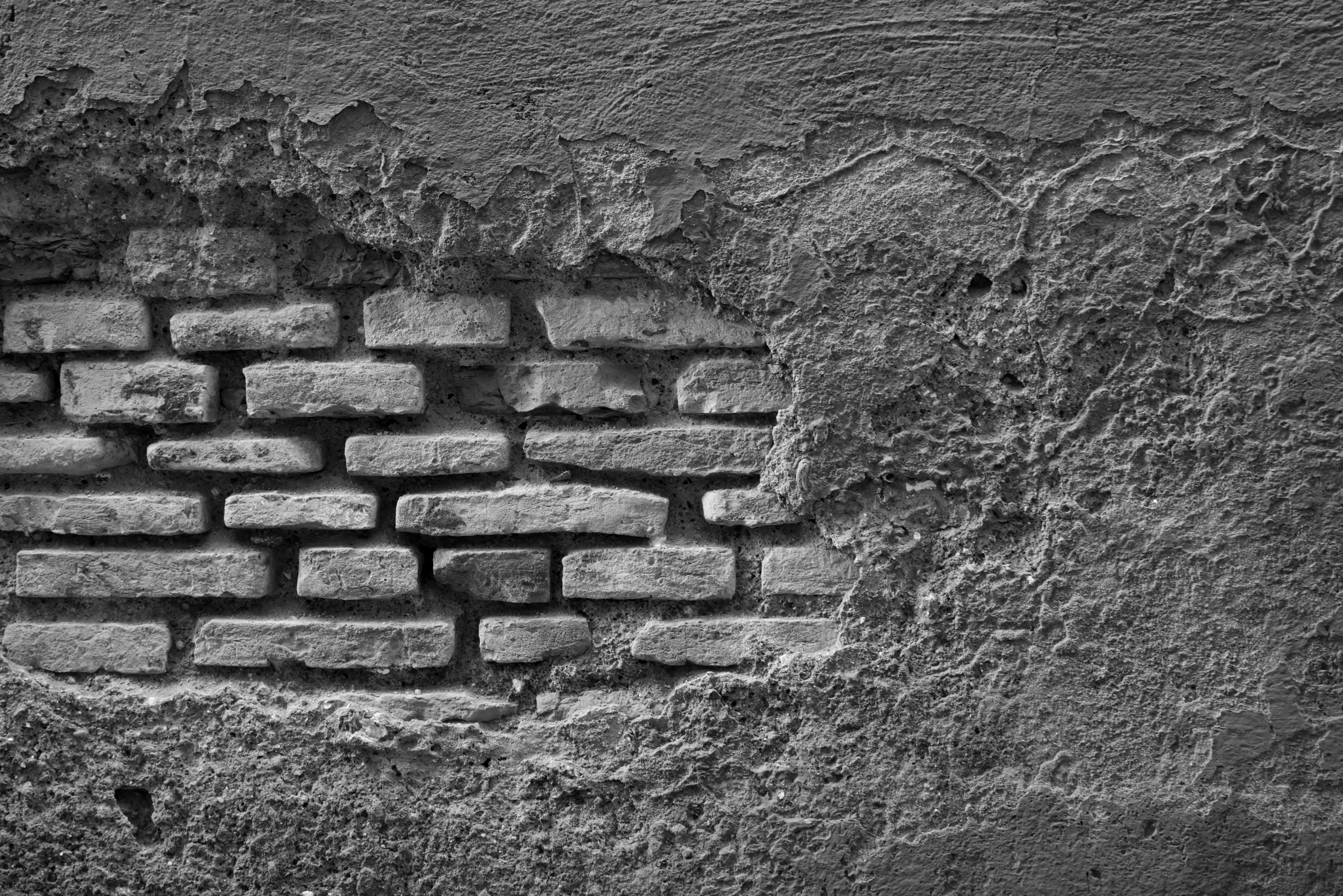 ingyenes Egy szabadon álló téglafal monokróm képe omladozó vakolattextúrával. Stockfotó