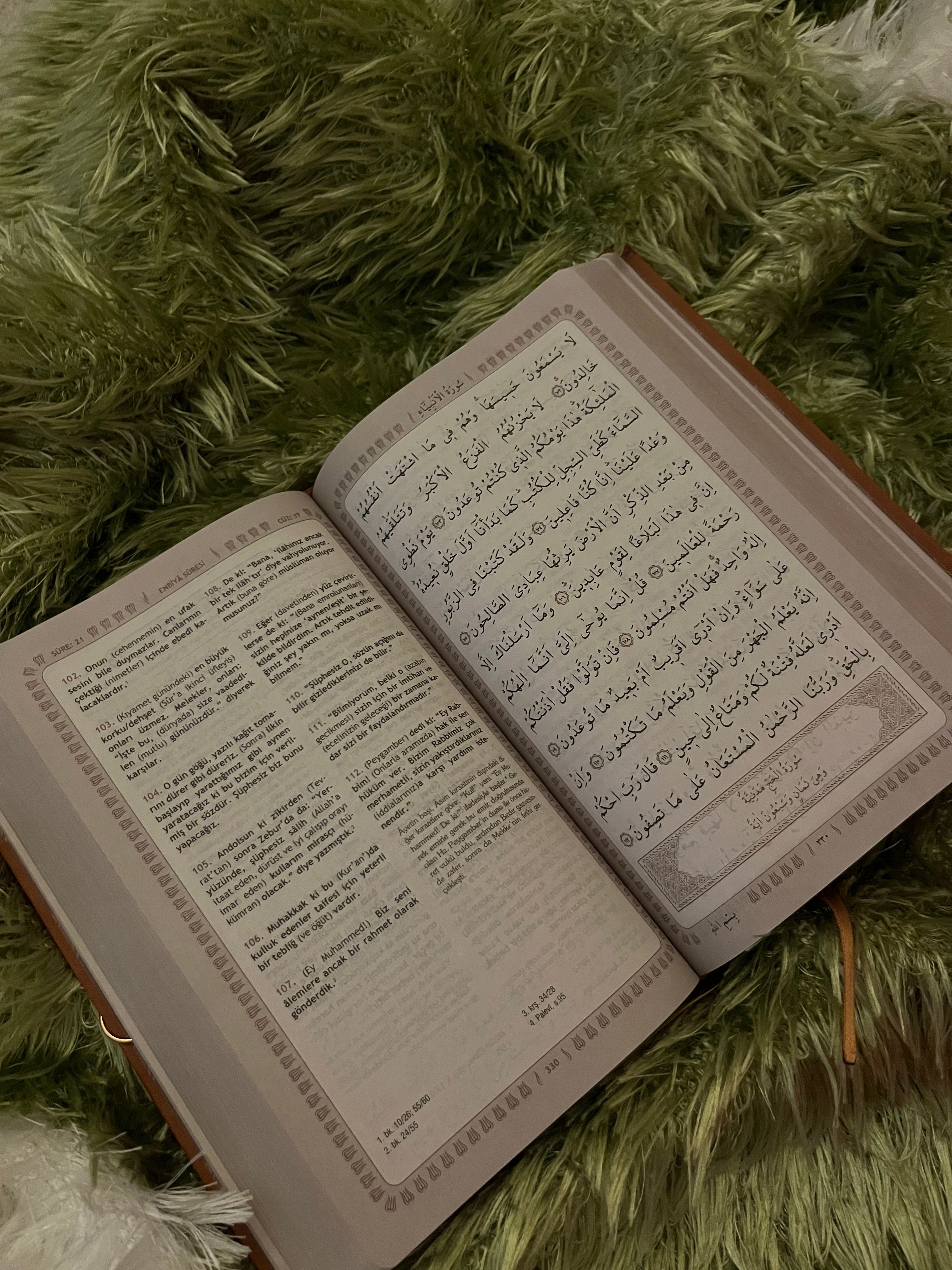 An open Quran on a soft green blanket, featuring Arabic text and translation.
