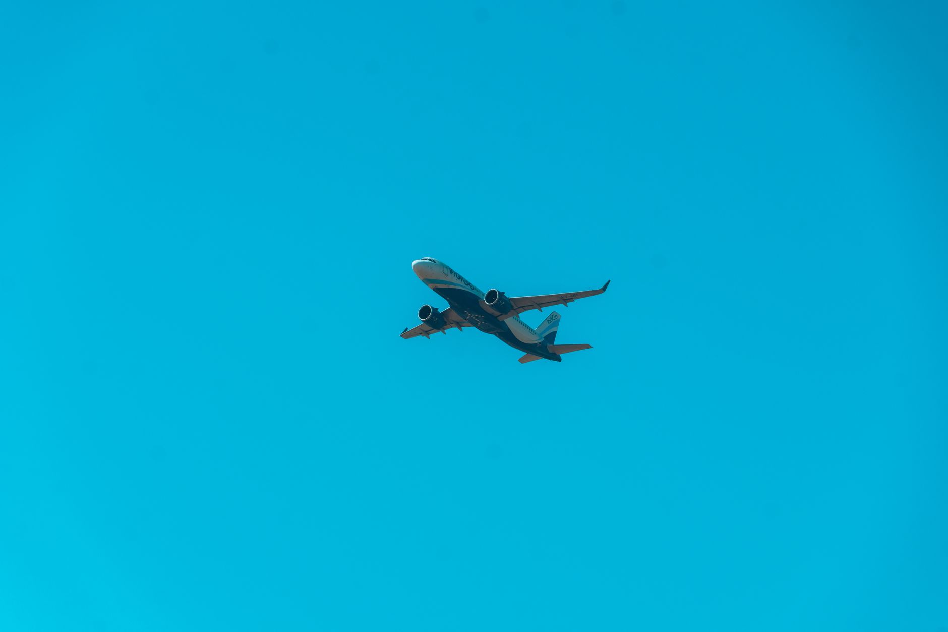 A commercial airplane flying high in a cloudless blue sky, representing modern air travel.