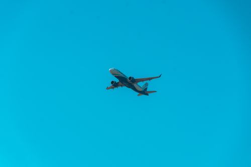 Free A commercial airplane flying high in a cloudless blue sky, representing modern air travel. Stock Photo