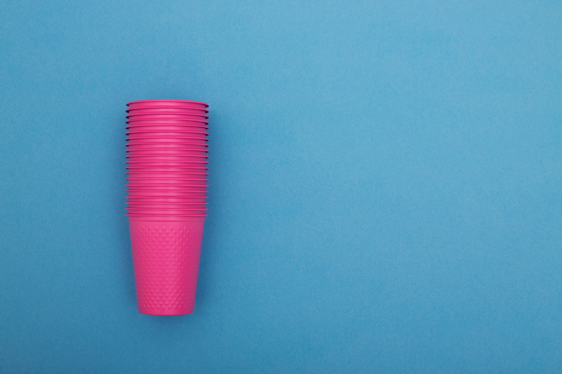 A stack of vibrant pink plastic cups stands out against a contrasting blue background, offering a striking visual contrast.