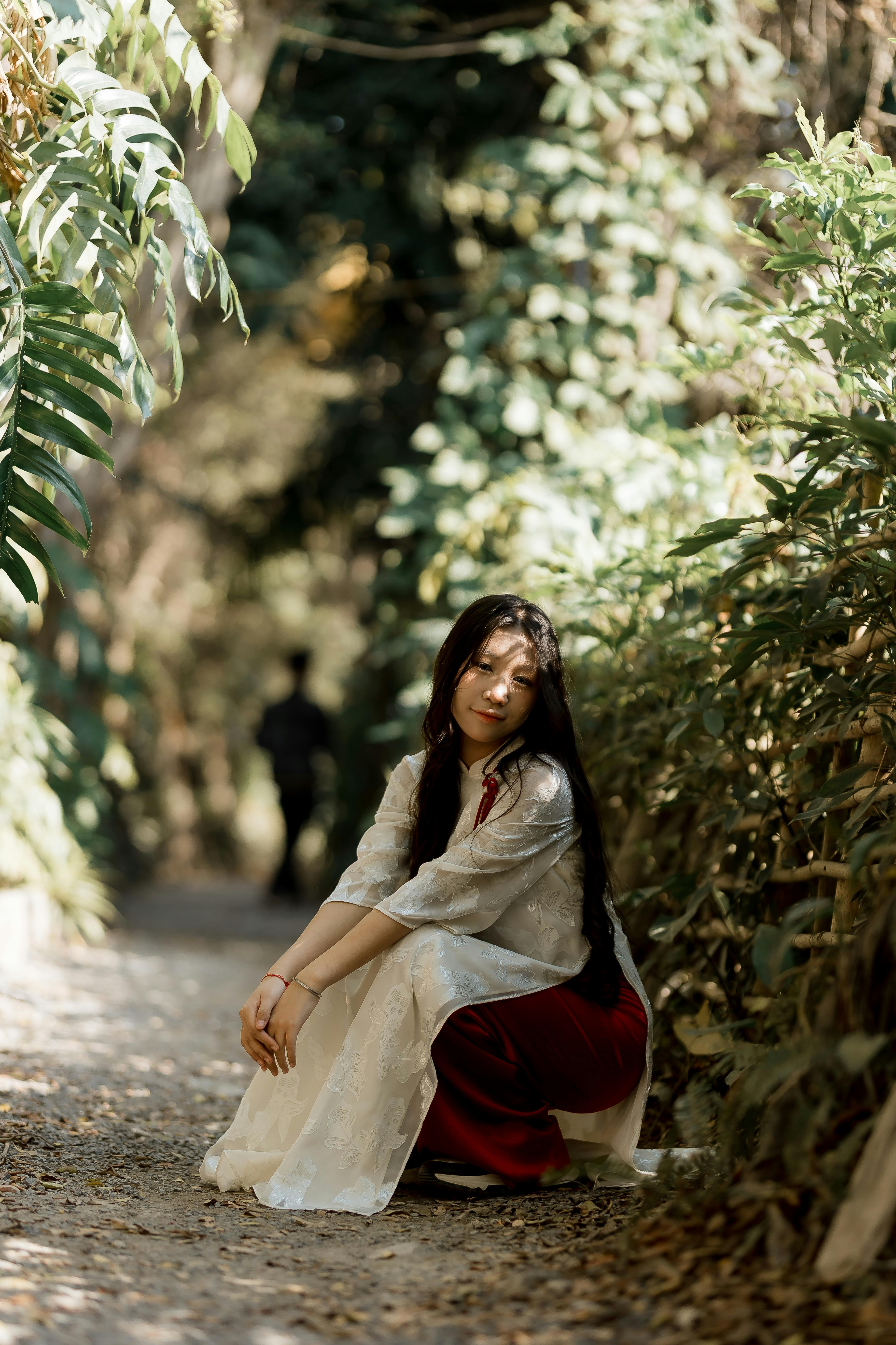 Δωρεάν Μια γαλήνια στιγμή καθώς μια γυναίκα με παραδοσιακή ενδυμασία κάθεται σε ένα καταπράσινο μονοπάτι στη φύση. Φωτογραφία από στοκ φωτογραφιών