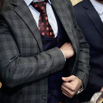 Close-up of a man in a designer suit, adjusting his tie, showcasing business fashion.