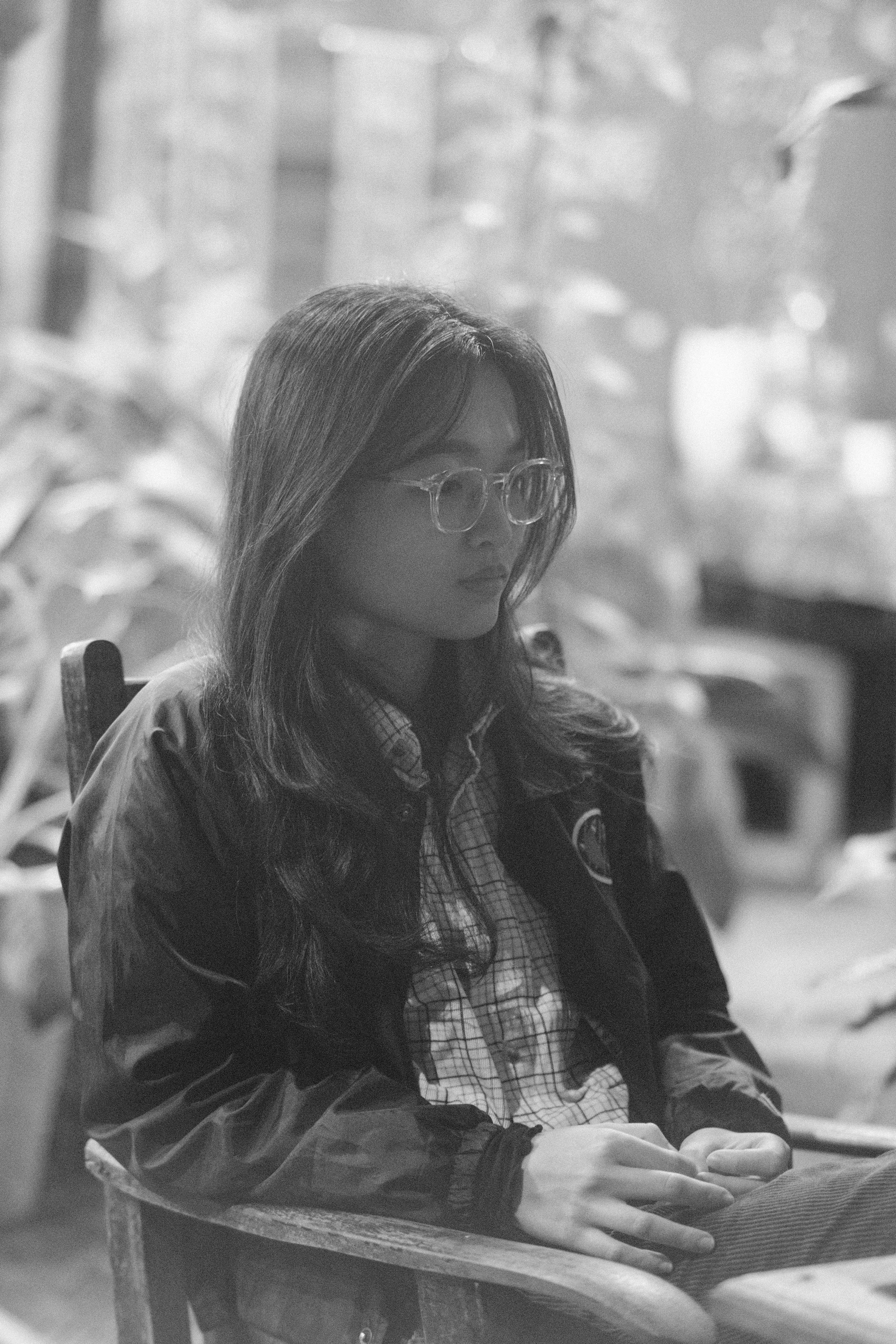 Gratis Ritratto in bianco e nero di una donna seduta all'aperto a Hội An, in Vietnam, che mostra un umore sereno e riflessivo. Foto a disposizione