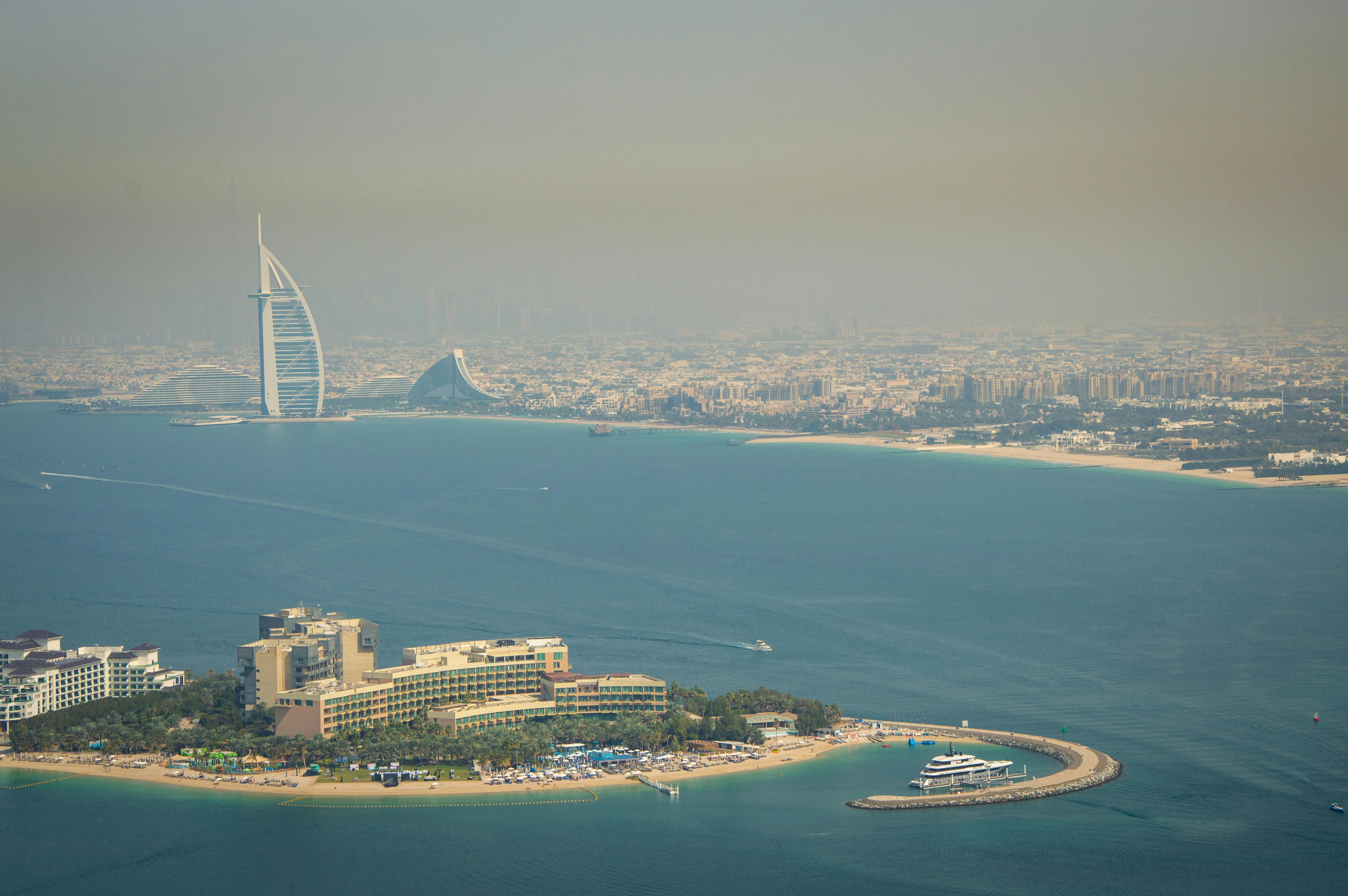 A breathtaking aerial view of the Dubai skyline featuring the iconic Burj Al Arab and pristine water