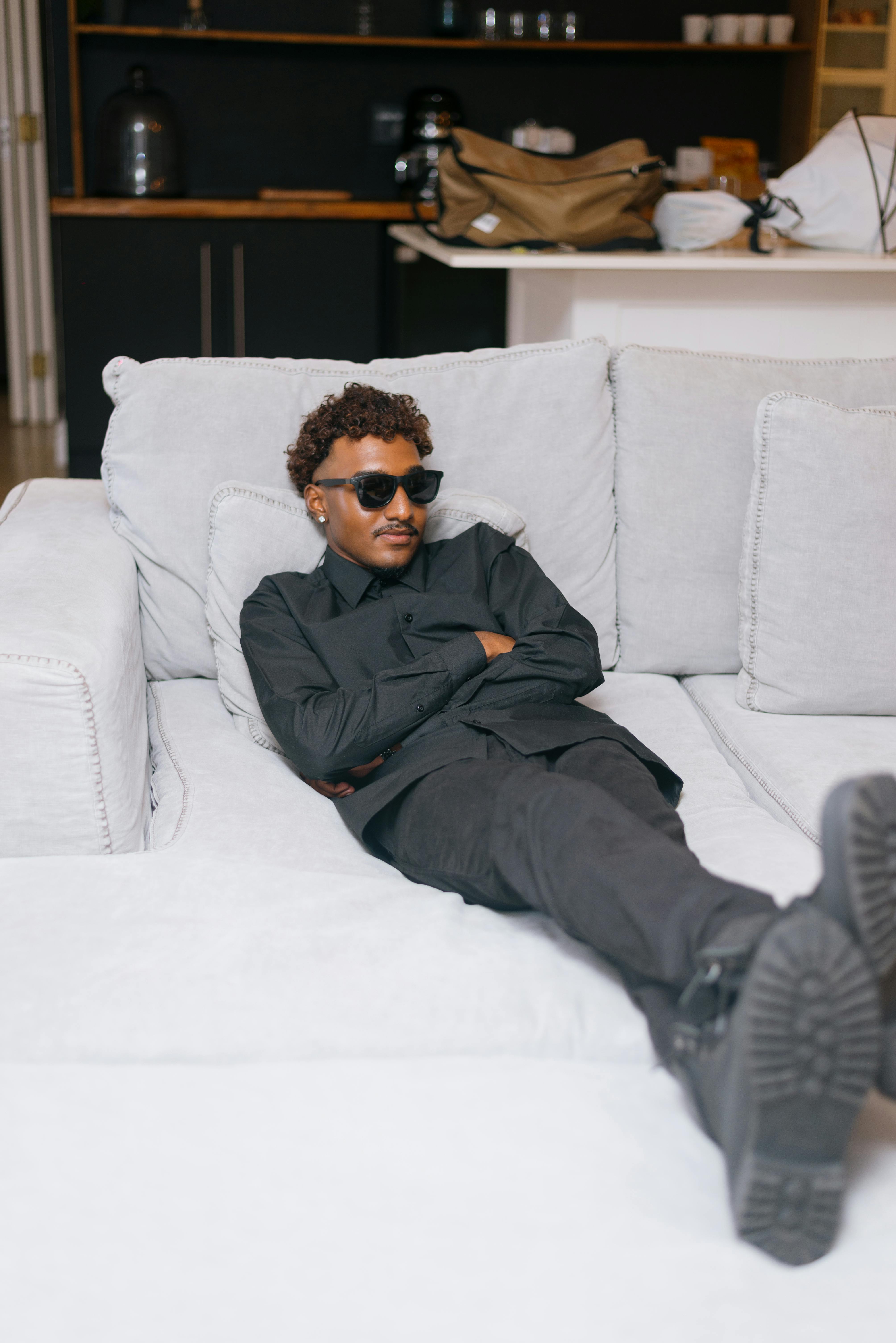 Δωρεάν Νεαρός άνδρας χαλαρώνει άνετα σε έναν καναπέ σε ένα μοντέρνο σαλόνι. Φωτογραφία από στοκ φωτογραφιών