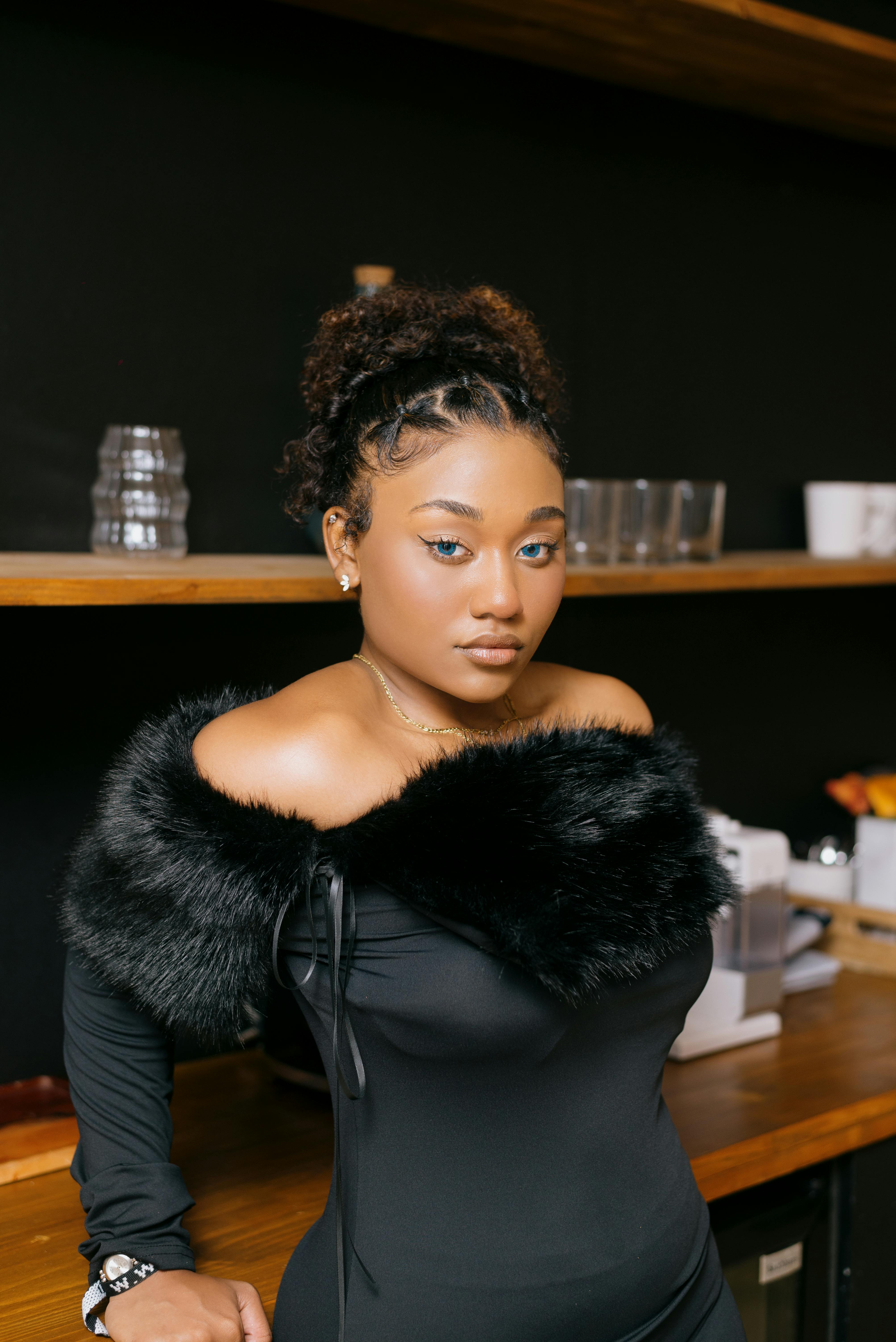 Gratis Una donna elegante, con un elegante abito nero, guarda con sicurezza dentro casa. Sofisticata e audace. Foto a disposizione