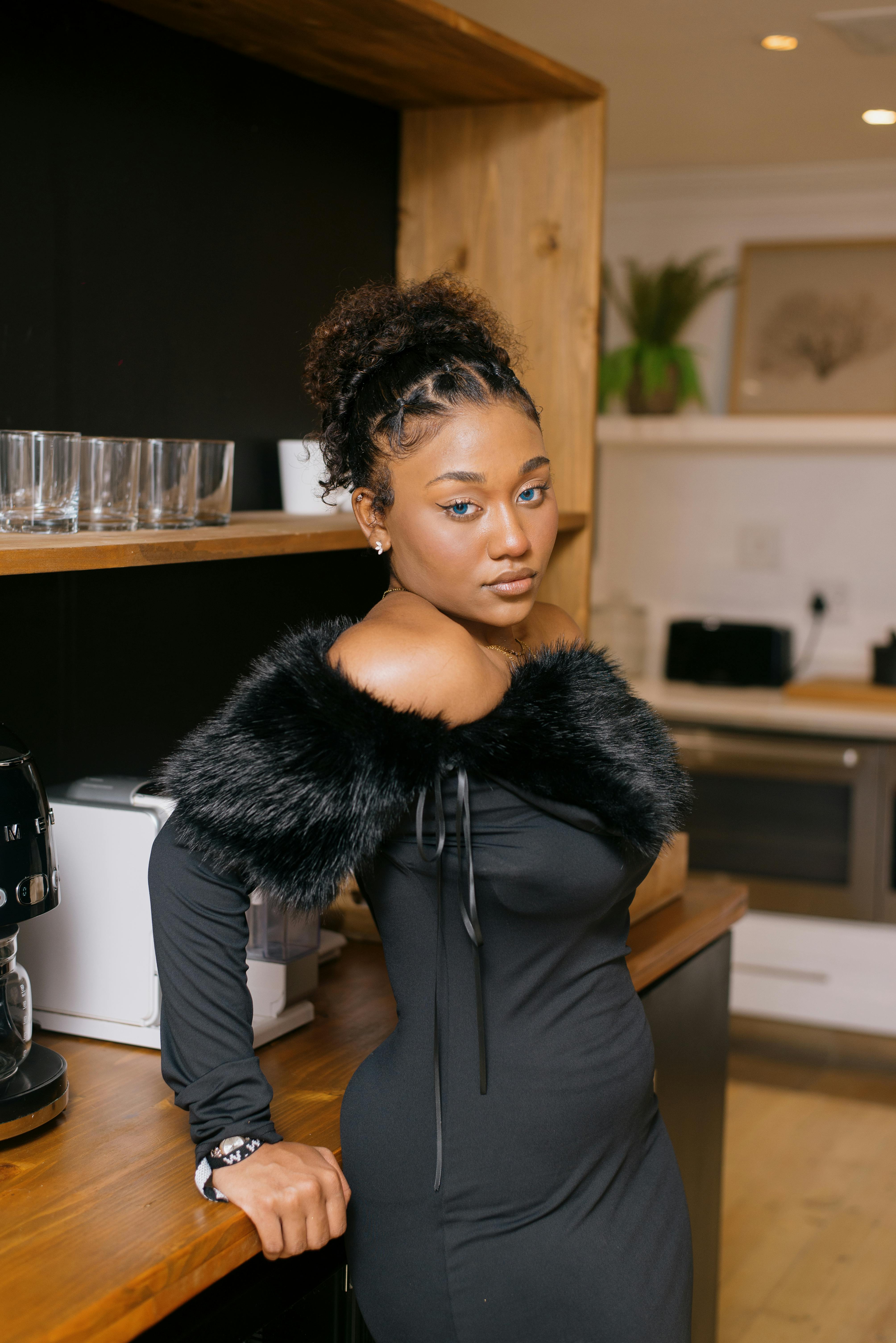 ingyenes Elegáns, fekete ruhás nő pózol beltérben, stílust és magabiztosságot sugározva. Stockfotó