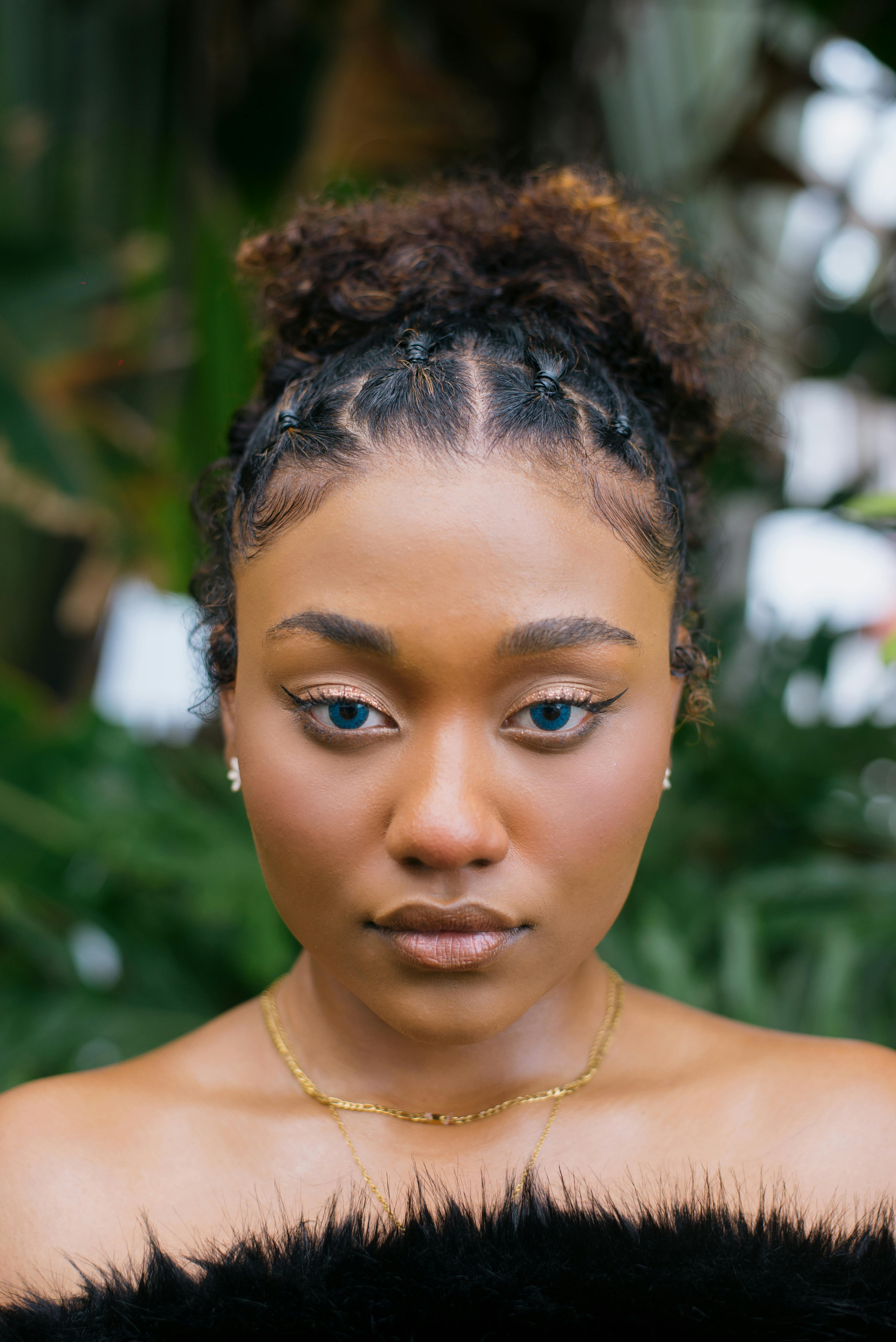 Miễn phí Ảnh cận cảnh một người phụ nữ với đôi mắt cuốn hút và mái tóc xoăn tự nhiên, chụp ngoài trời. Ảnh lưu trữ