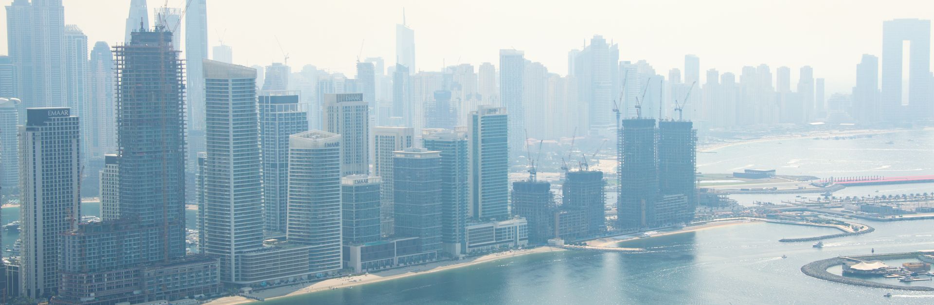 A person enjoys a rooftop pool with a stunning view of the Dubai skyline and waterfront.
