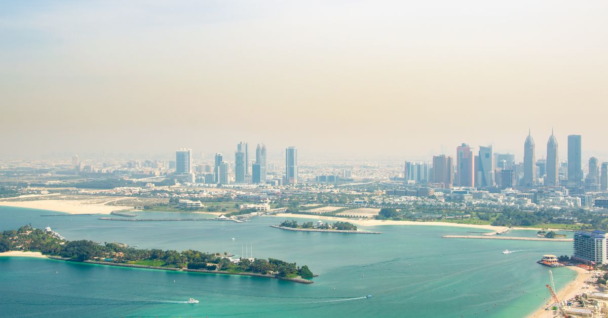 Stunning aerial view of Dubai's skyline with a beautiful coastline and clear blue waters.