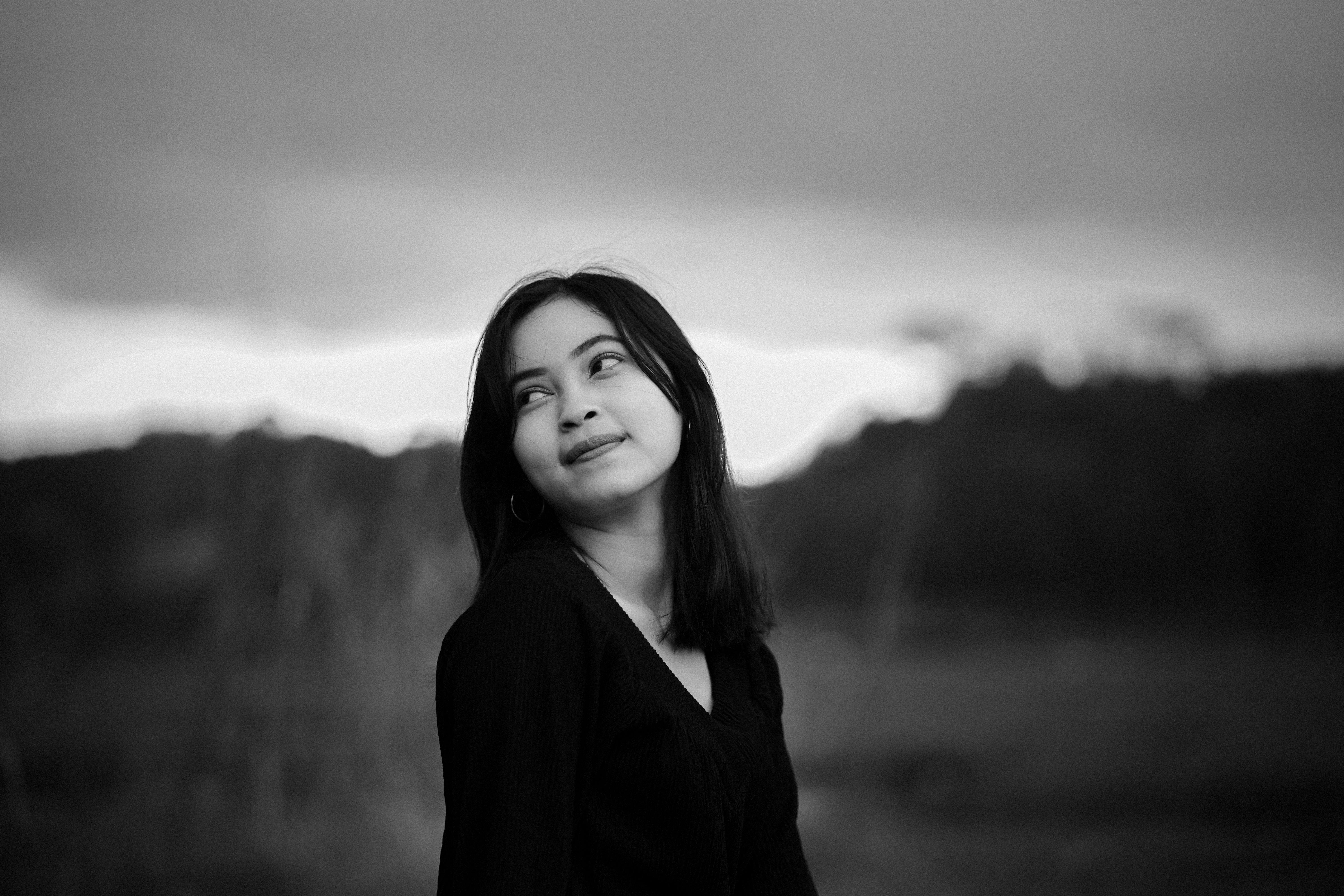 Free A captivating black and white portrait of a young woman looking upwards outdoors. Stock Photo