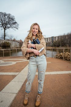 一位穿着休闲装、拿着书和水瓶的白人妇女，正站在人行道上微笑