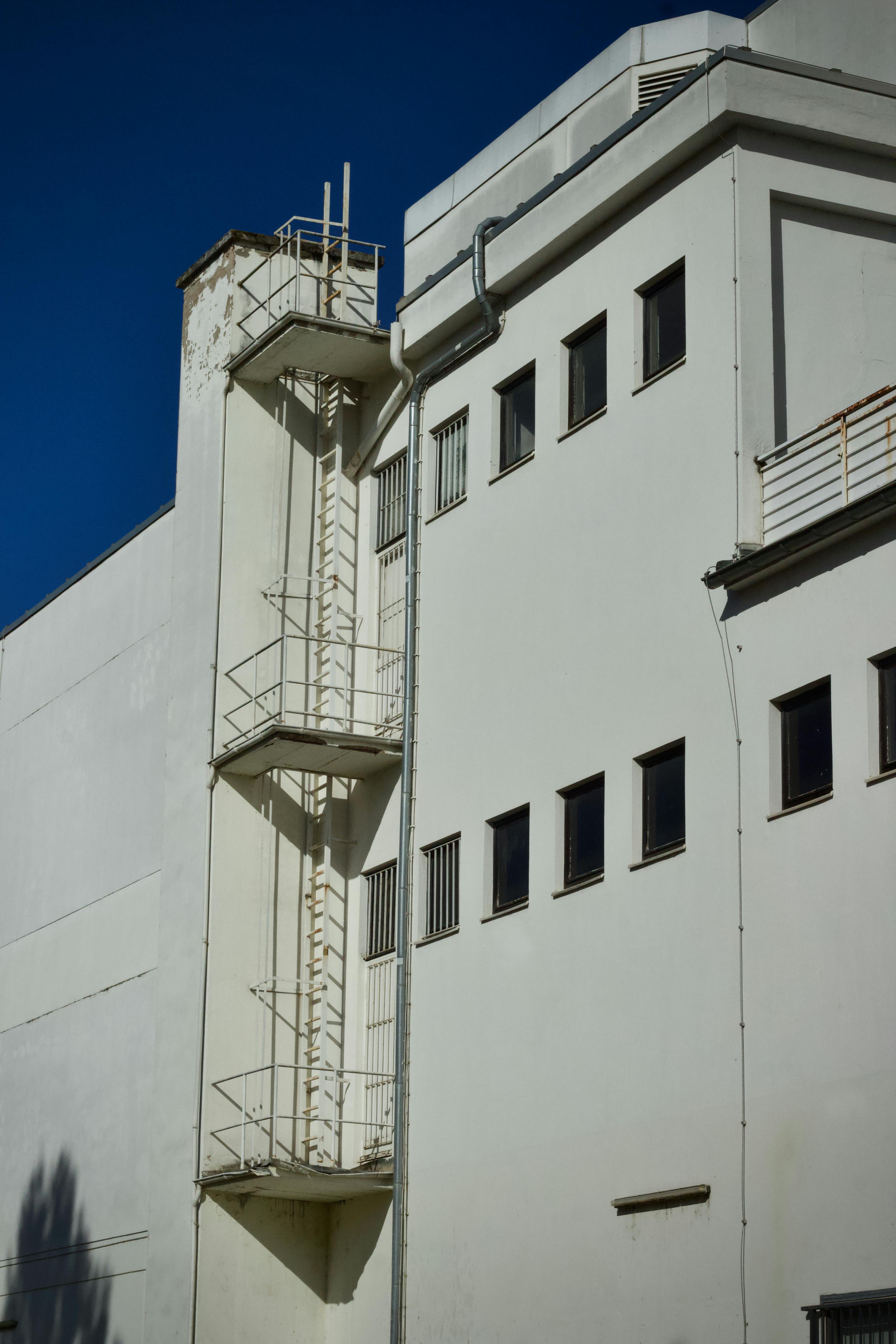 gratis Wit gebouw met een metalen brandtrap tegen een helderblauwe hemel. Stockfoto