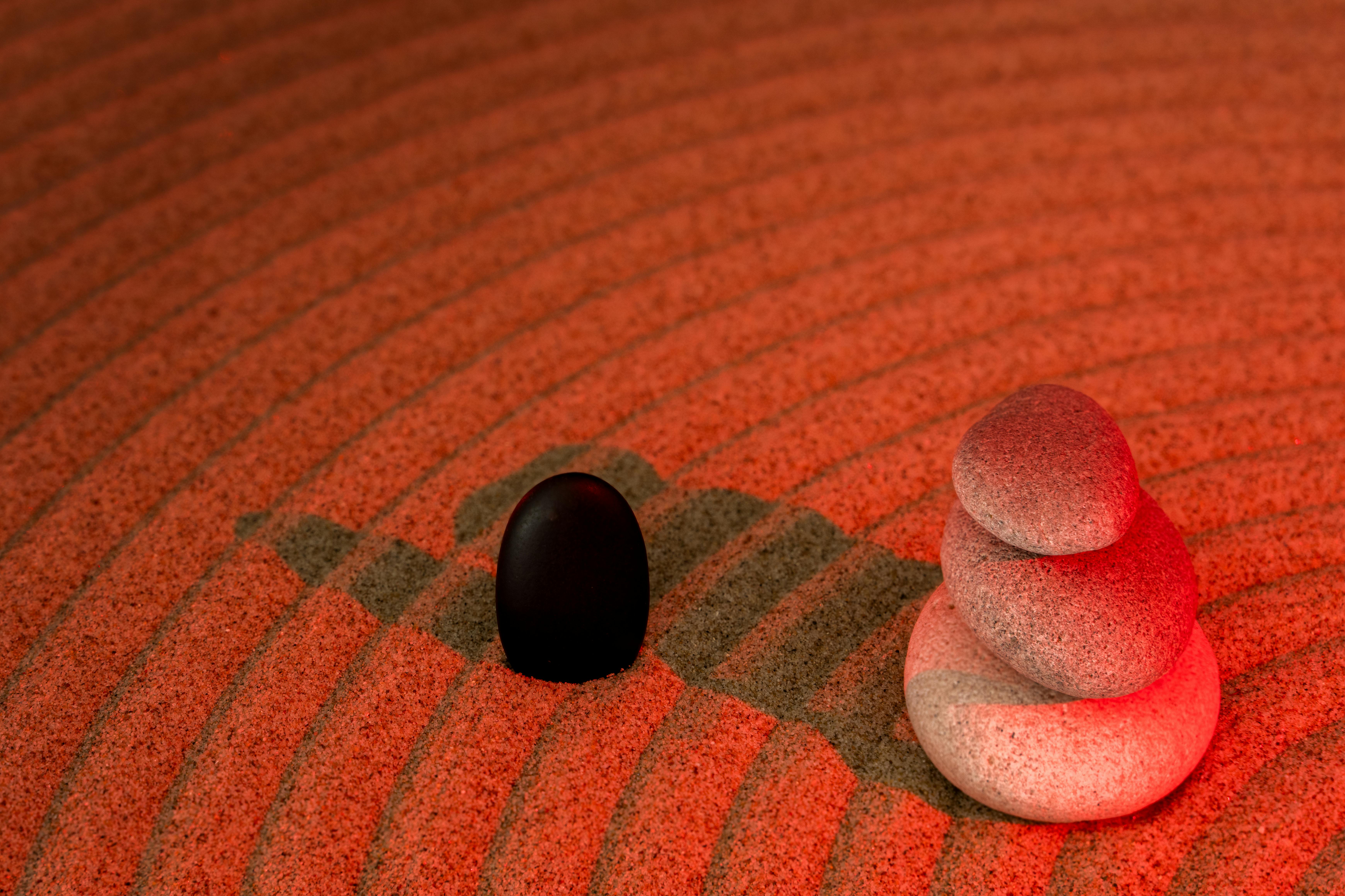 Gratis Et fredfyldt arrangement af zensten på bølget rødt sand, der fremhæver ro. Lagerfoto