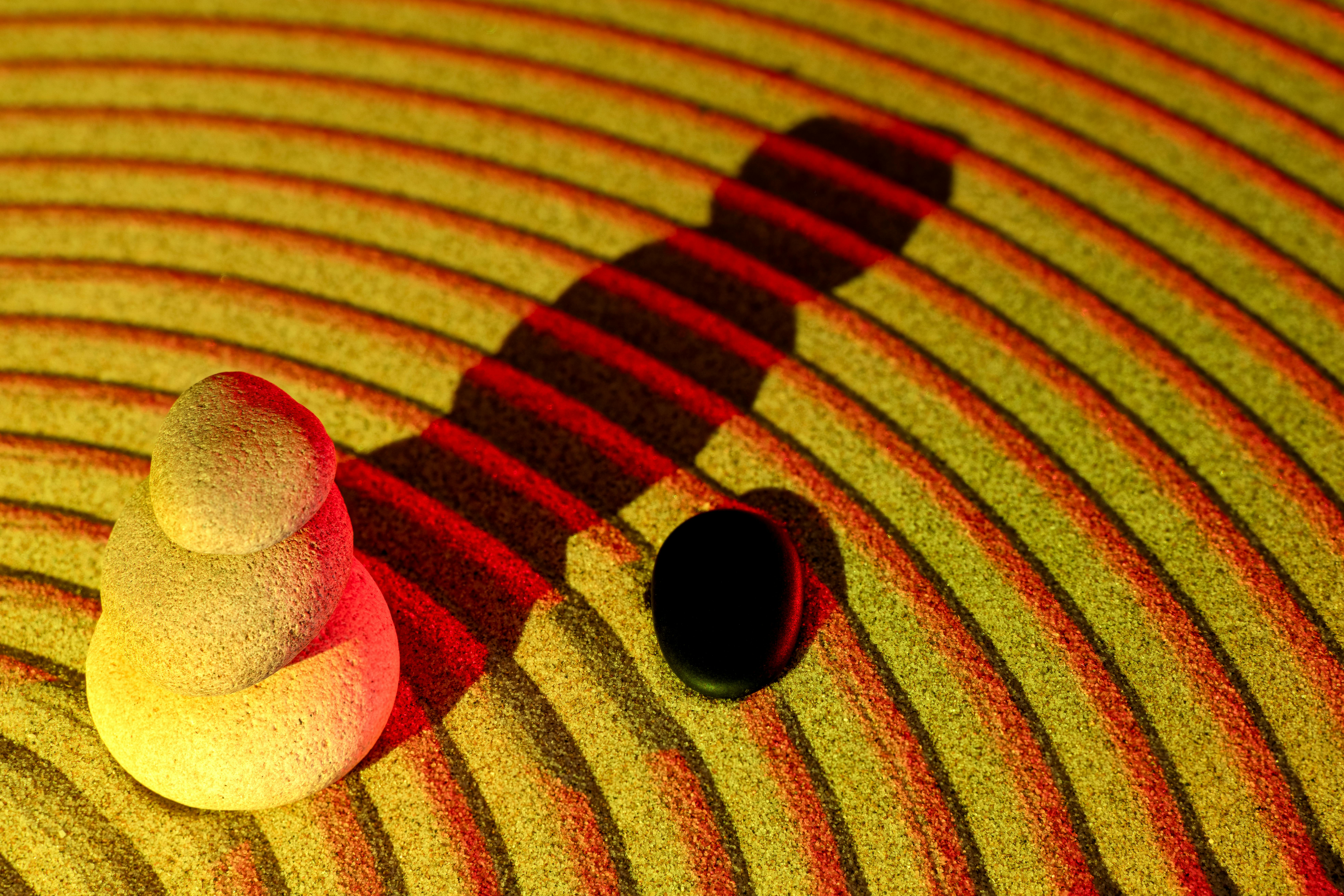 gratis Elegant gestapelde stenen creëren een zen-sfeer in een rood verlichte zandtuin. Stockfoto