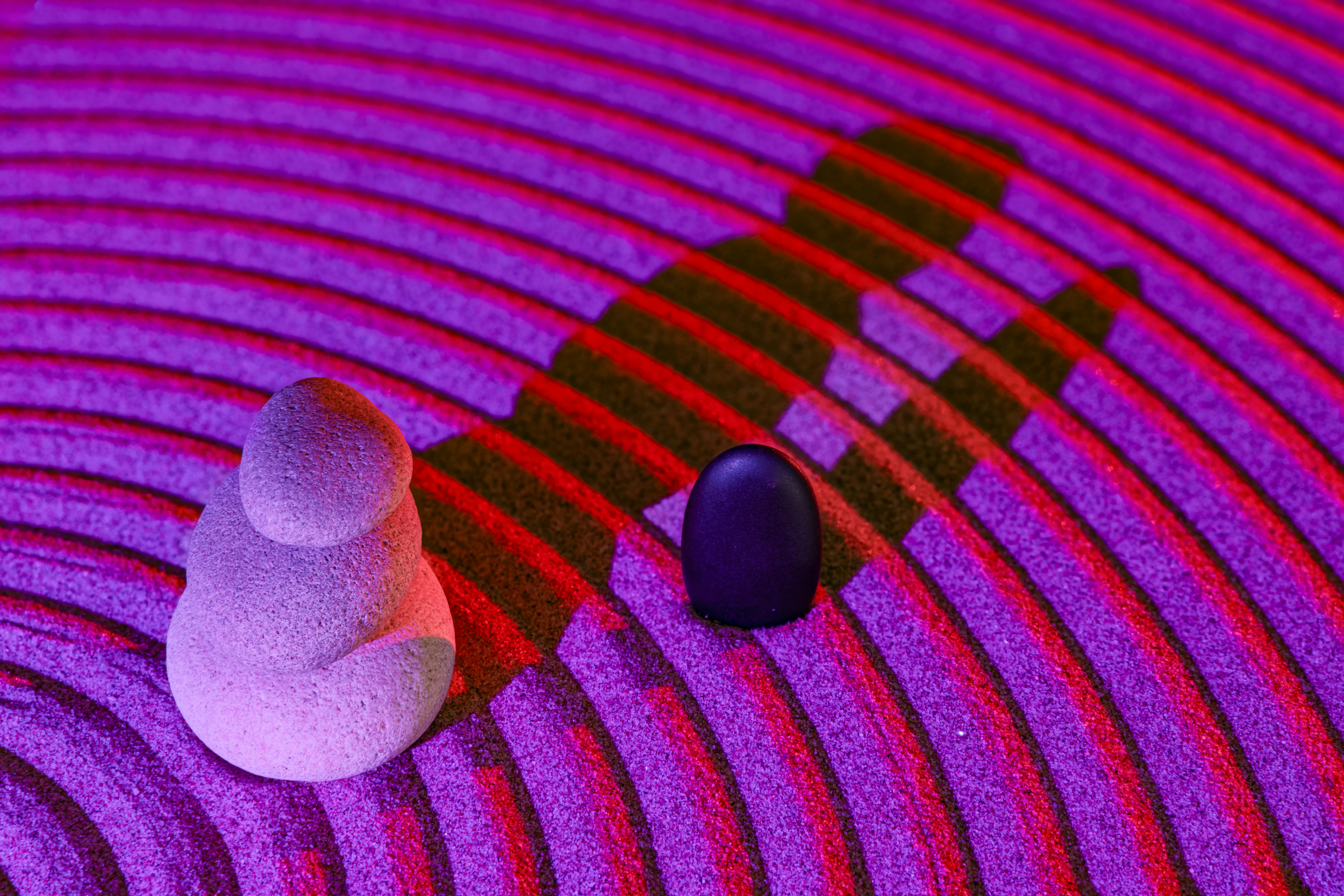 Free Stacked stones in artistic lighting on sand patterns creating a zen ambiance. Stock Photo