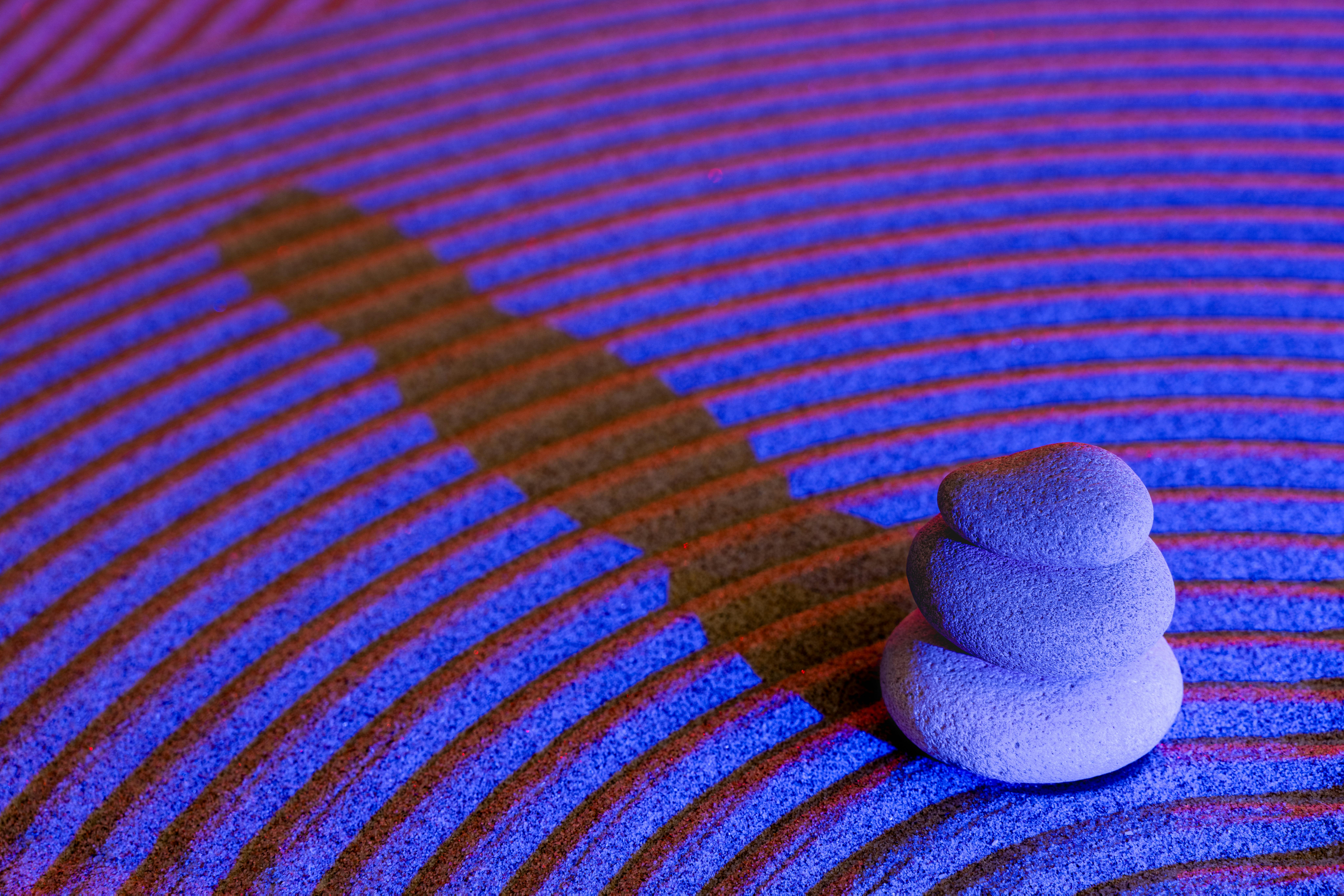 Gratis Pietre zen impilate illuminate da luce blu e rossa su una superficie strutturata con un rilassante gioco di ombre. Foto a disposizione