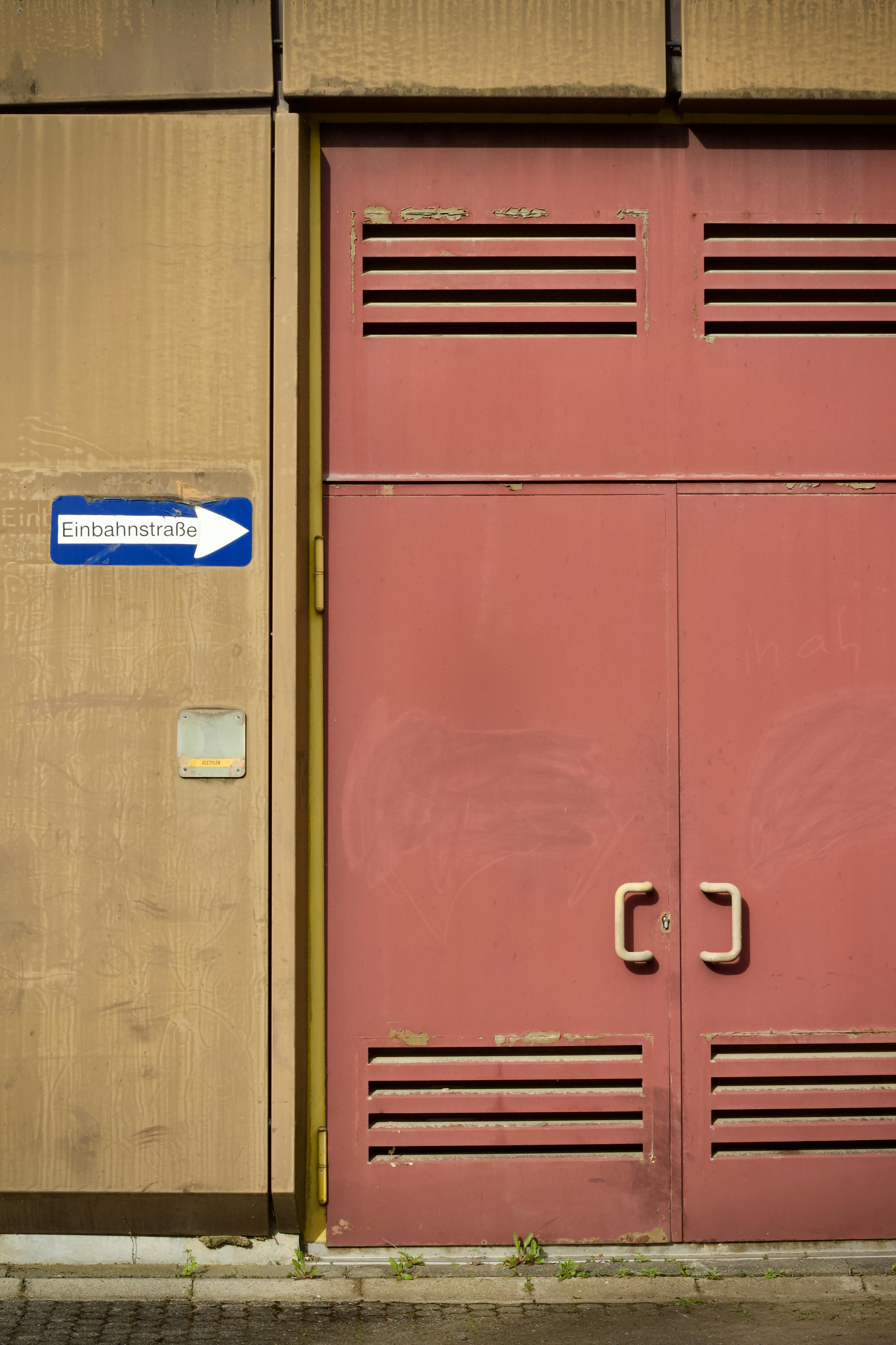 gratis Rode industriële deur en Einbahnstraße-bord als symbool voor stedelijke straatarchitectuur. Stockfoto