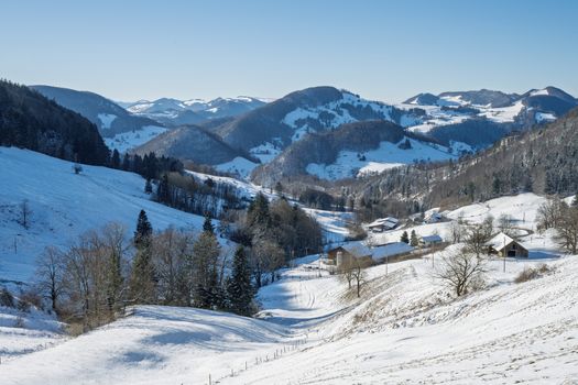 Breathtaking view of a snow-covered rural landscape with rolling hills and scattered houses in winter.
