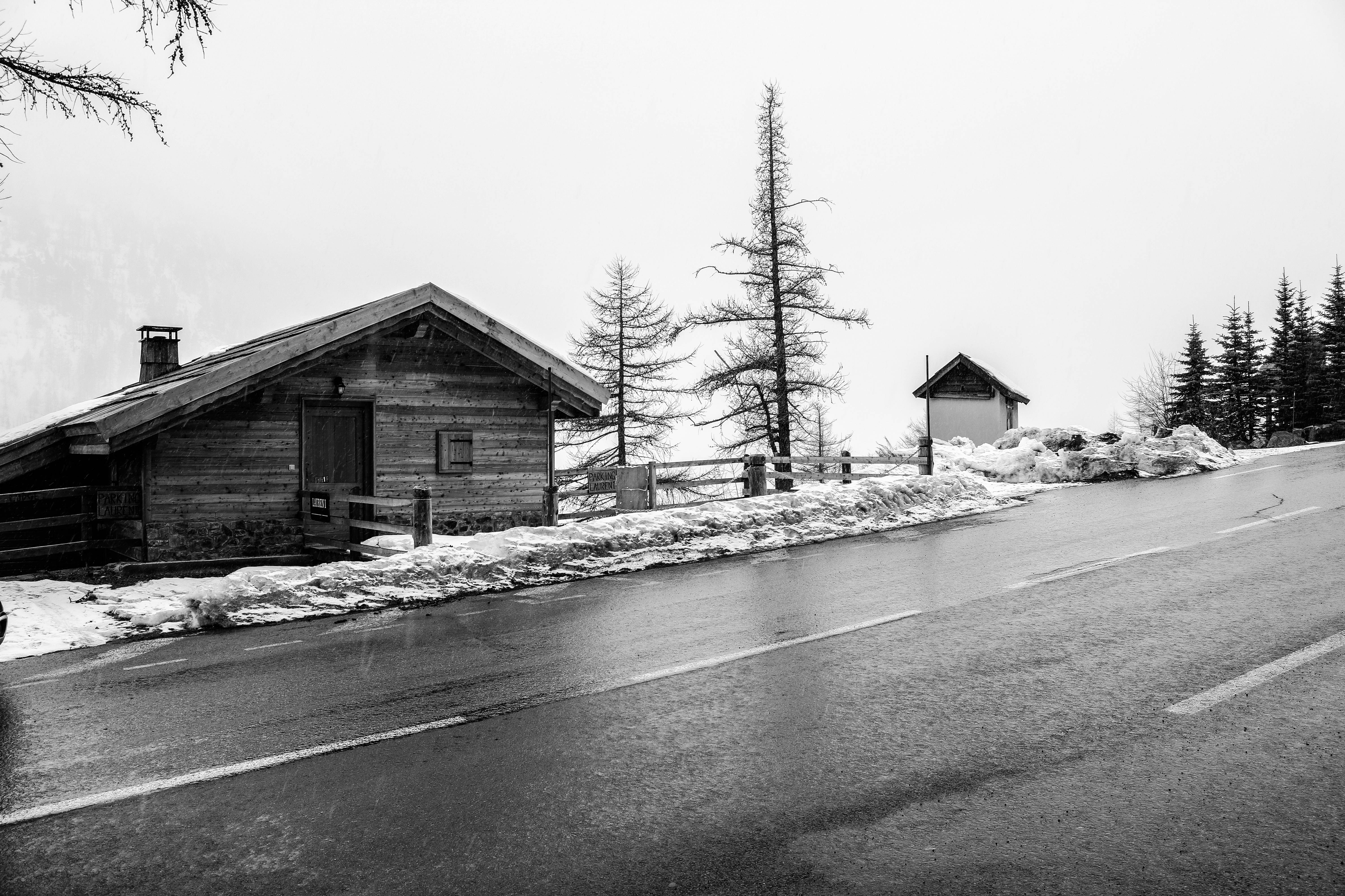 Une image en noir et blanc d'un chalet de montagne enneigé, baigné d'une atmosphère hivernale sereine.