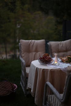 Elegant outdoor dining scene with candlelight at dusk, featuring a soft table setting.