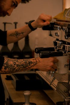 A tattooed barista prepares espresso at a café in Ankara, showcasing coffee culture.