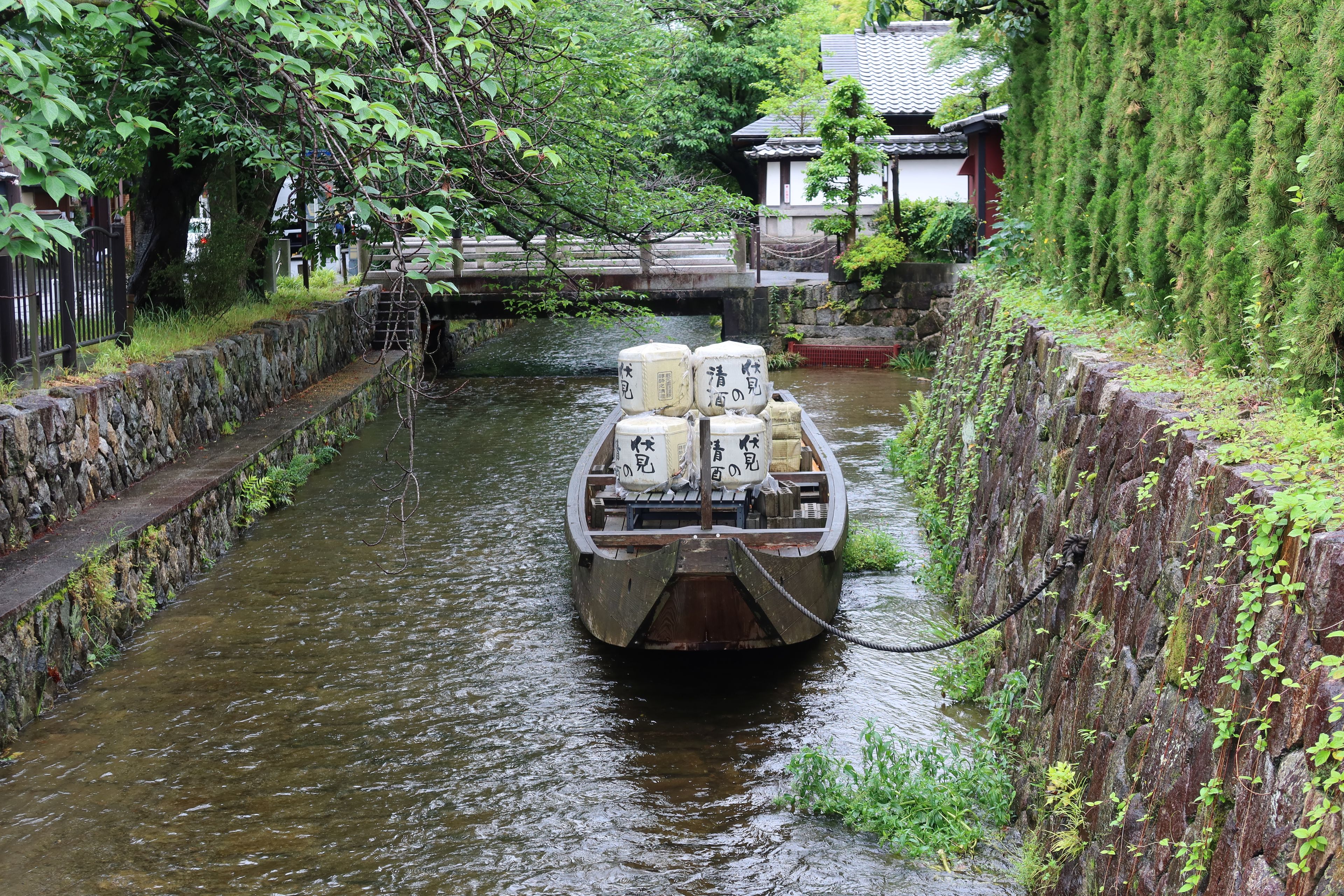 Traditional Japanese boat with sake barrels cruising a serene canal in Kyoto, Japan.