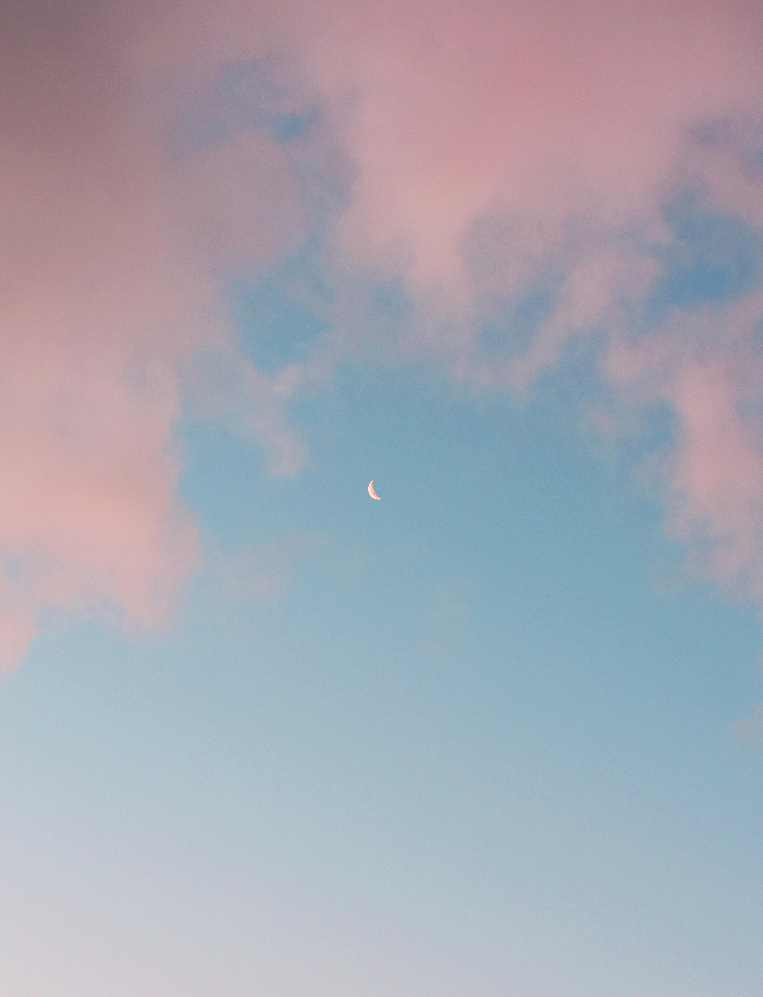 Gratis Un cielo meraviglioso con una luna crescente circondata da nuvole rosa durante il tramonto. Foto a disposizione