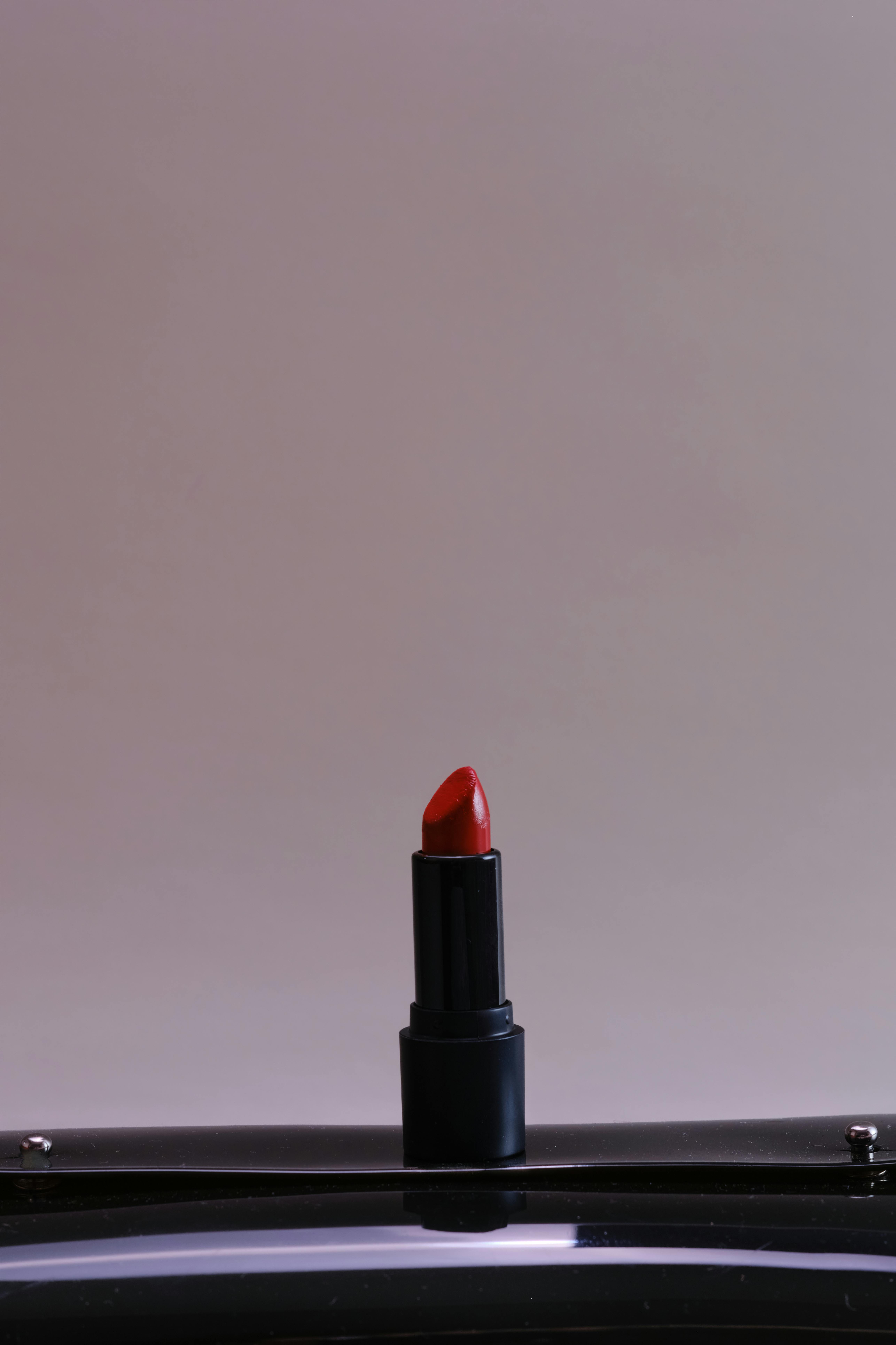 Zadarmo Minimalistická fotka klasického červeného rúžu na neutrálnom pozadí. Fotka z fotobanky