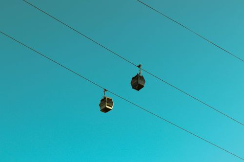 Free Two cable cars suspended on wires, set against a clear blue sky, showcasing modern transportation. Stock Photo