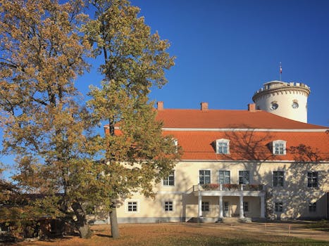 Scenic view of Cesis Castle with vibrant autumn leaves under a clear blue sky.