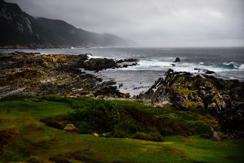 Free Stunning view of a rugged coastline with waves crashing against the rocky shore under a cloudy sky. Stock Photo