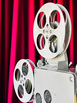 Close-up of a vintage film projector against a vibrant red curtain, capturing a classic cinema vibe.