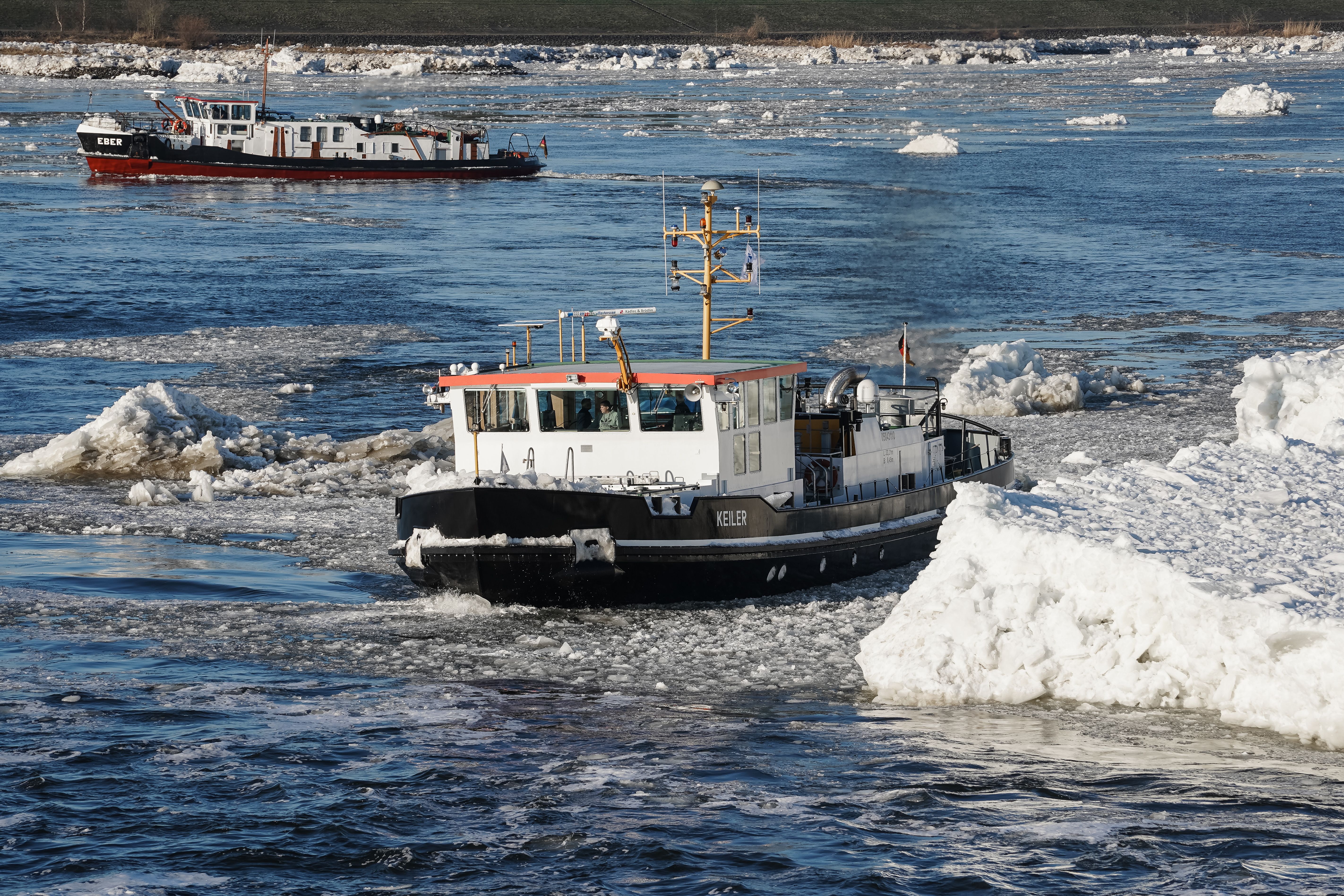 Two icebreakers clear a path through the frozen Elbe River in Geesthacht, Germany.
