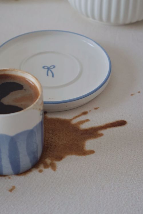 Free An artistic view of a spilled coffee creating a pattern on a white tablecloth. Stock Photo