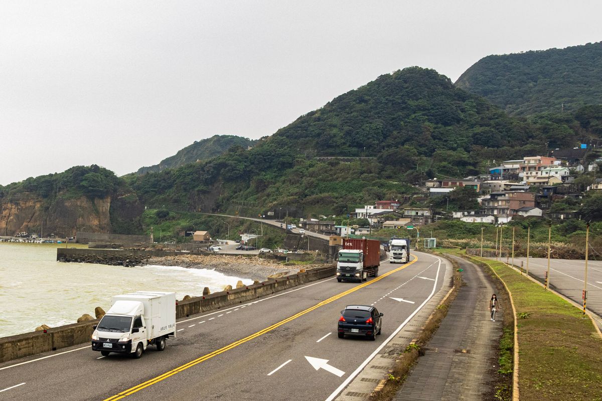 White box lorries driving along a coastal highway — the large blank body panels that a full wrap turns into advertising space