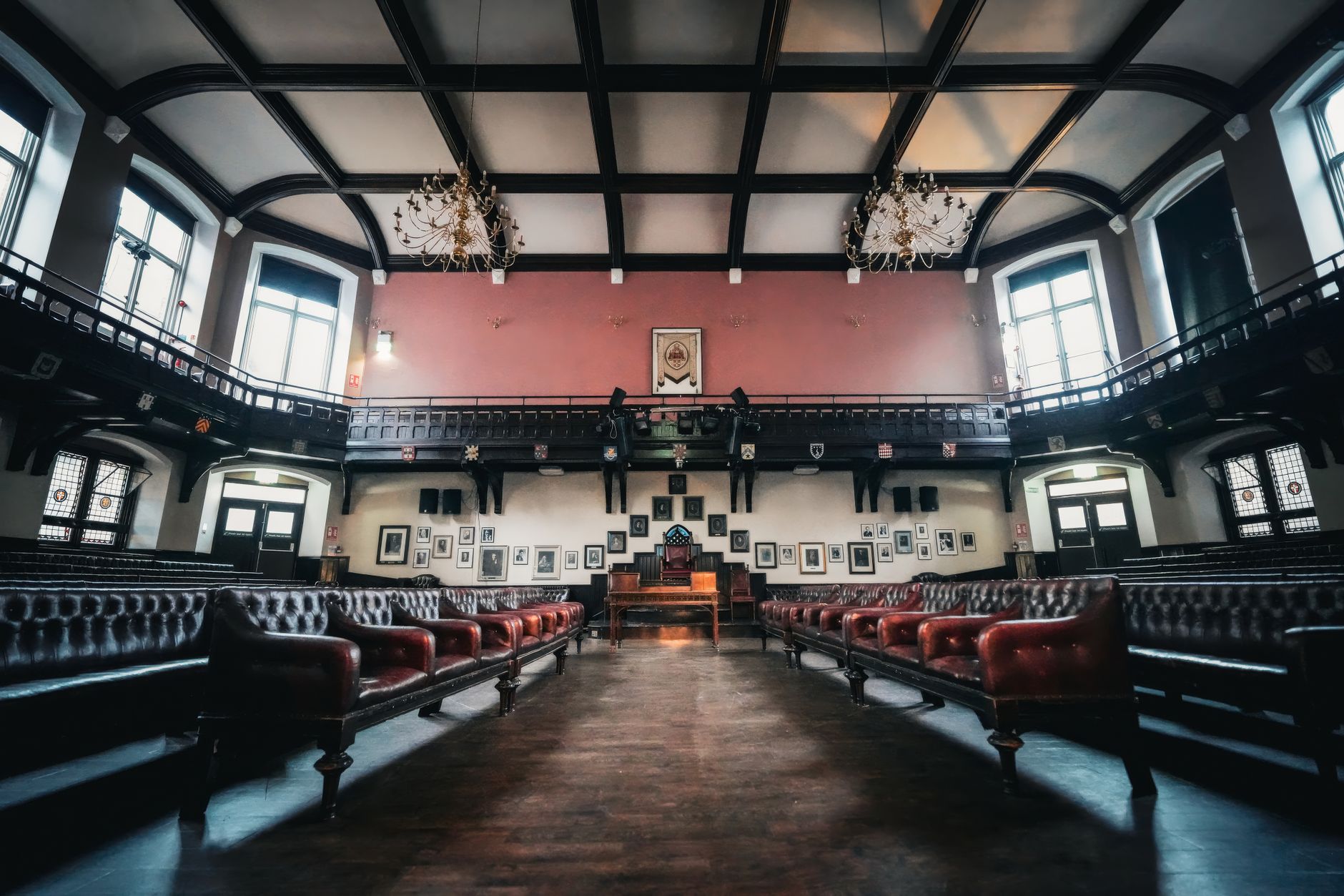 A grand empty interior with vintage leather seats, chandeliers, and wood paneling.