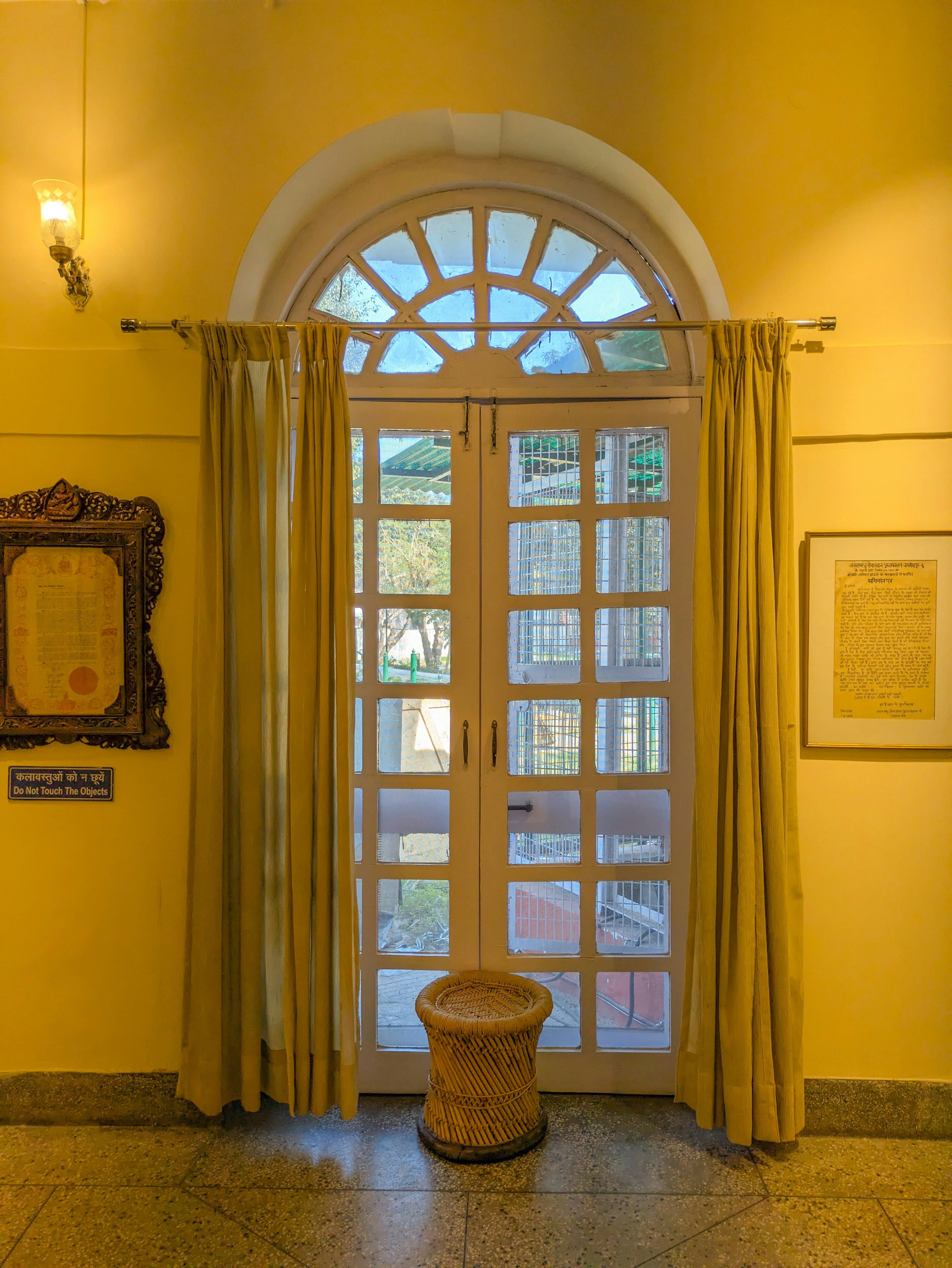 Gratis Et klassisk buet vindue med gardiner i et interiør i New Delhi, der tilbyder en blød, varm atmosfære. Lagerfoto