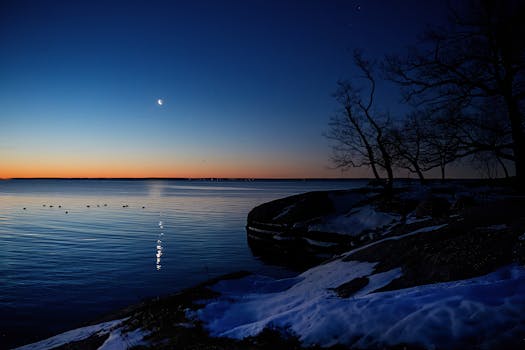 Peaceful winter twilight at Cove Island Park in Stamford, Connecticut, showcasing snow, crescent moon, and serene dawn sky.