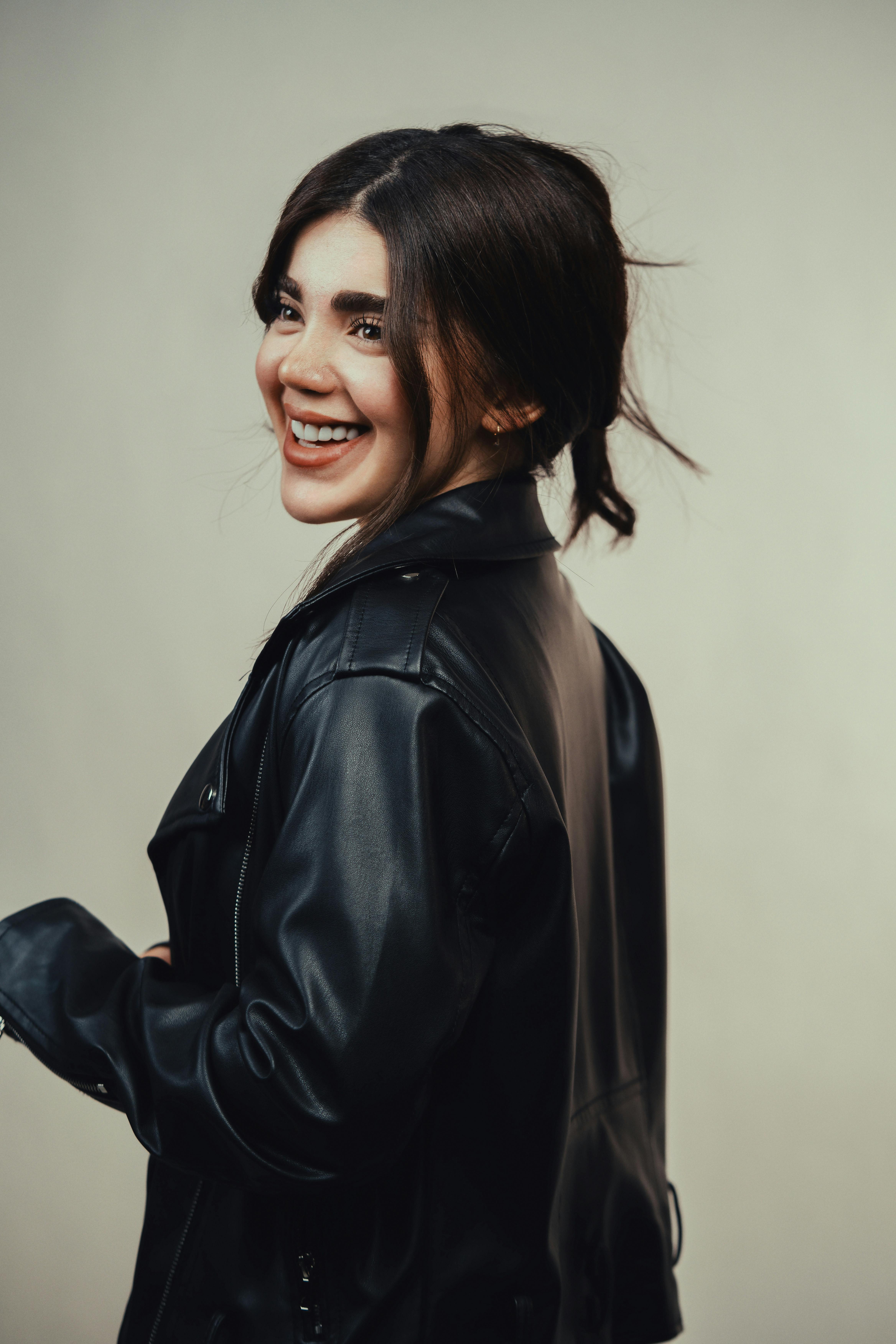 Gratis Ritratto di una donna allegra che indossa una giacca di pelle e sorride con sicurezza. Foto a disposizione