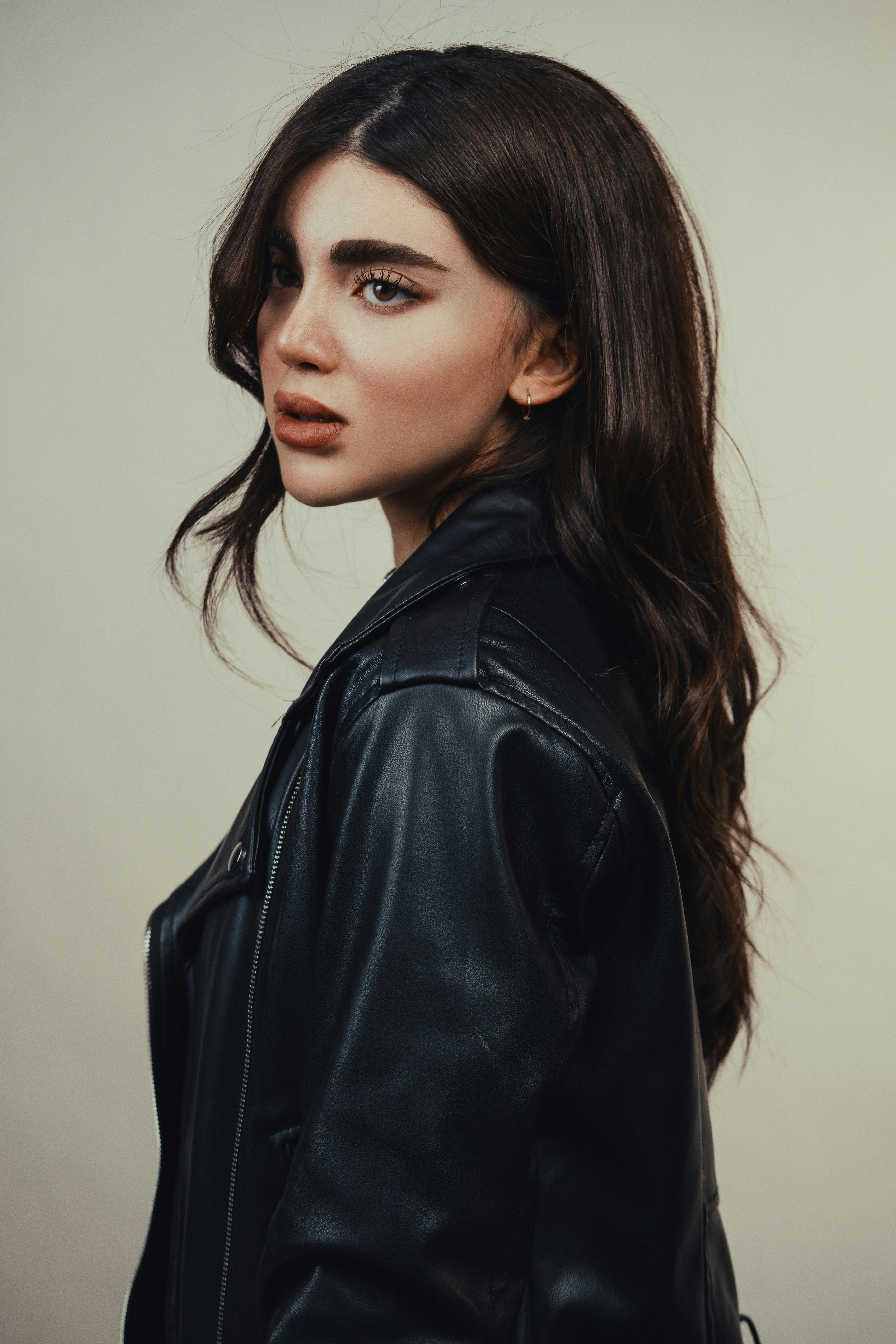 Miễn phí Hình ảnh cận cảnh một người phụ nữ mặc áo khoác da đen trên nền trung tính. Ảnh lưu trữ