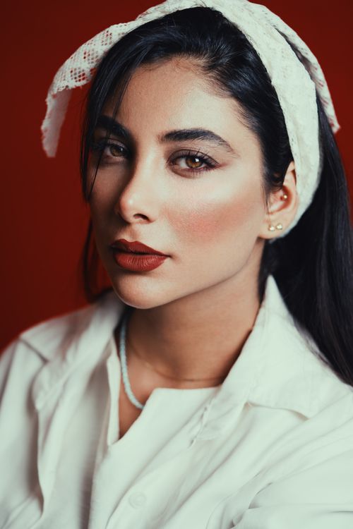 Free Elegant portrait of a woman with a lace headband against a red backdrop. Stock Photo